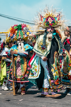 Vibrant Mexican costumes at a cultural festival parade outdoors.