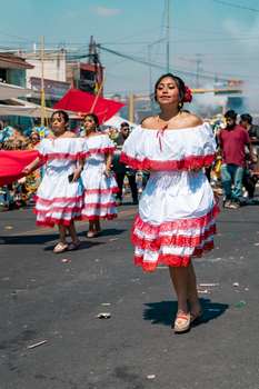 Women in vibrant costumes march in a traditional street parade.