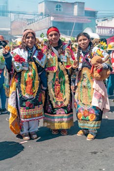 Three women in traditional Mexican attire at a vibrant cultural festival.