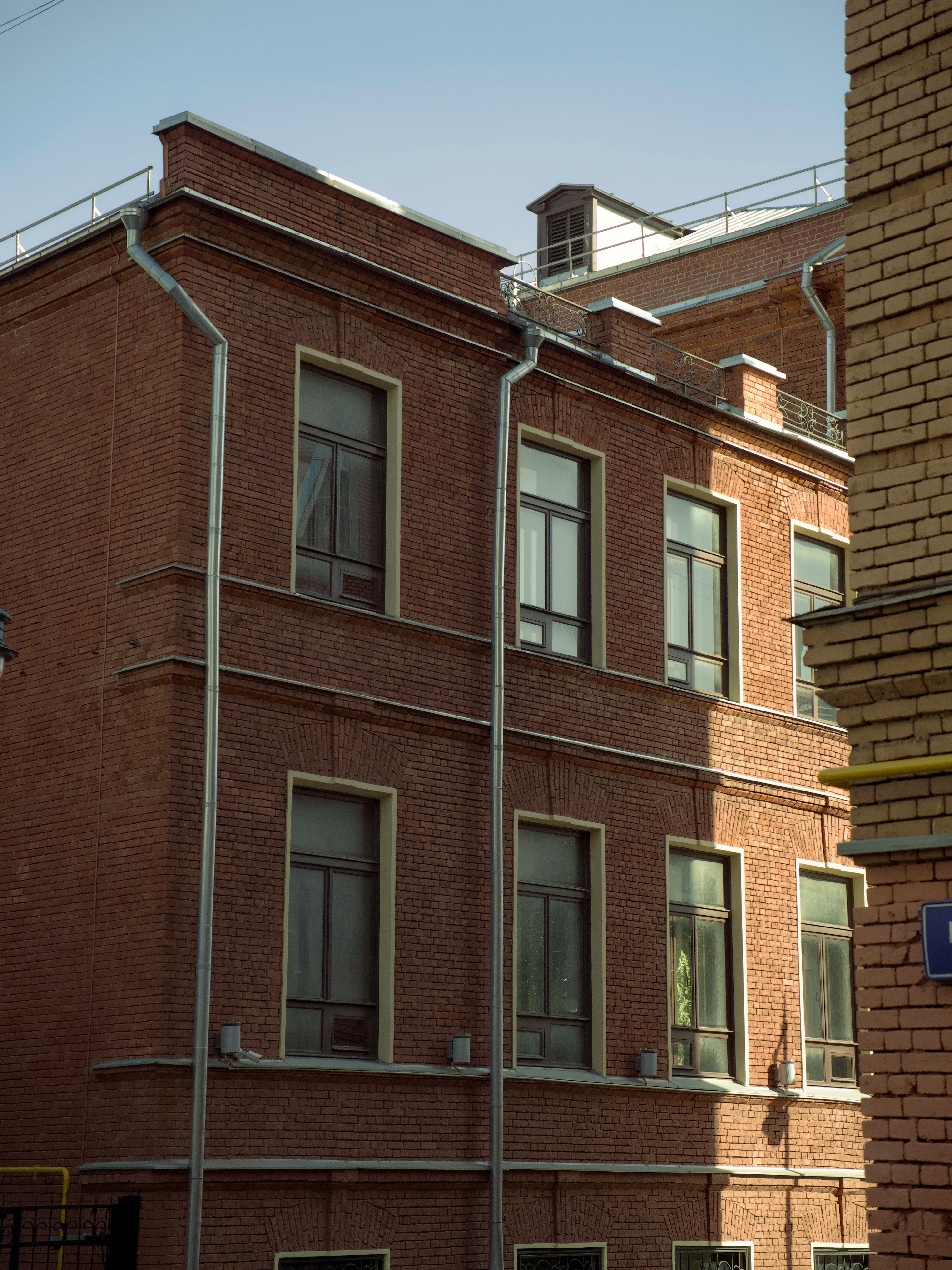 bezplatná Tradiční budova z červených cihel s několika okny je osvětlena slunečním světlem a představuje klasický architektonický design. Základová fotografie