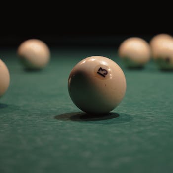 Focused shot of a numbered billiard ball on a green pool table under dim lighting.