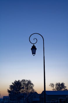 Silhouetted streetlamp during a tranquil early morning sunrise.
