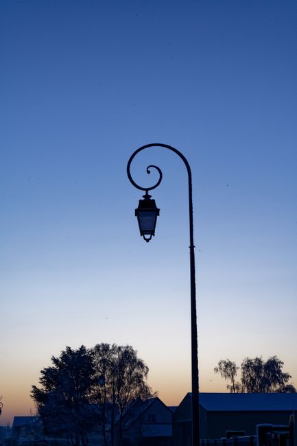 Silhouetted streetlamp during a tranquil early morning sunrise.
