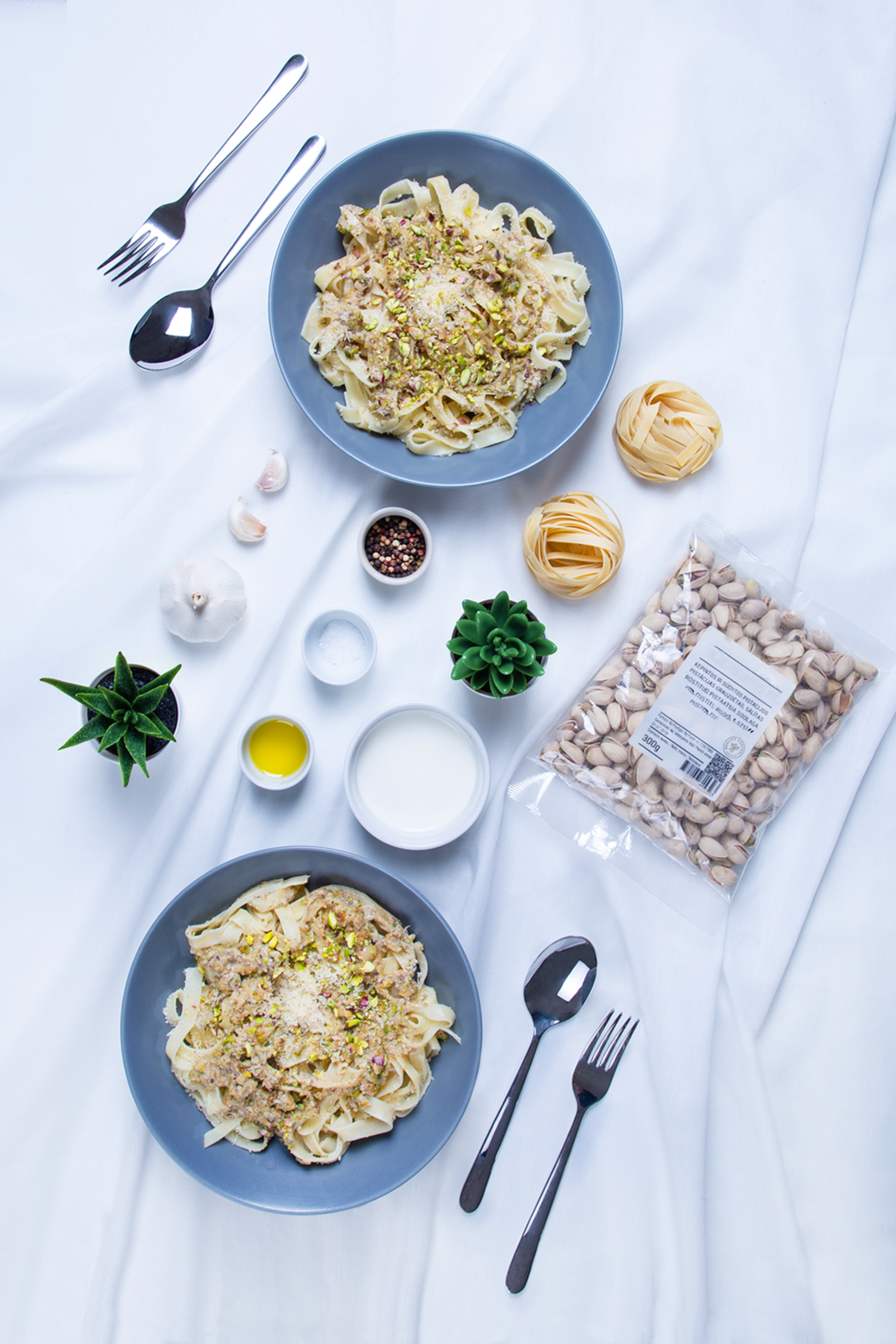 Top view of pasta dinner setting with pistachios and ingredients, perfect for a romantic meal.