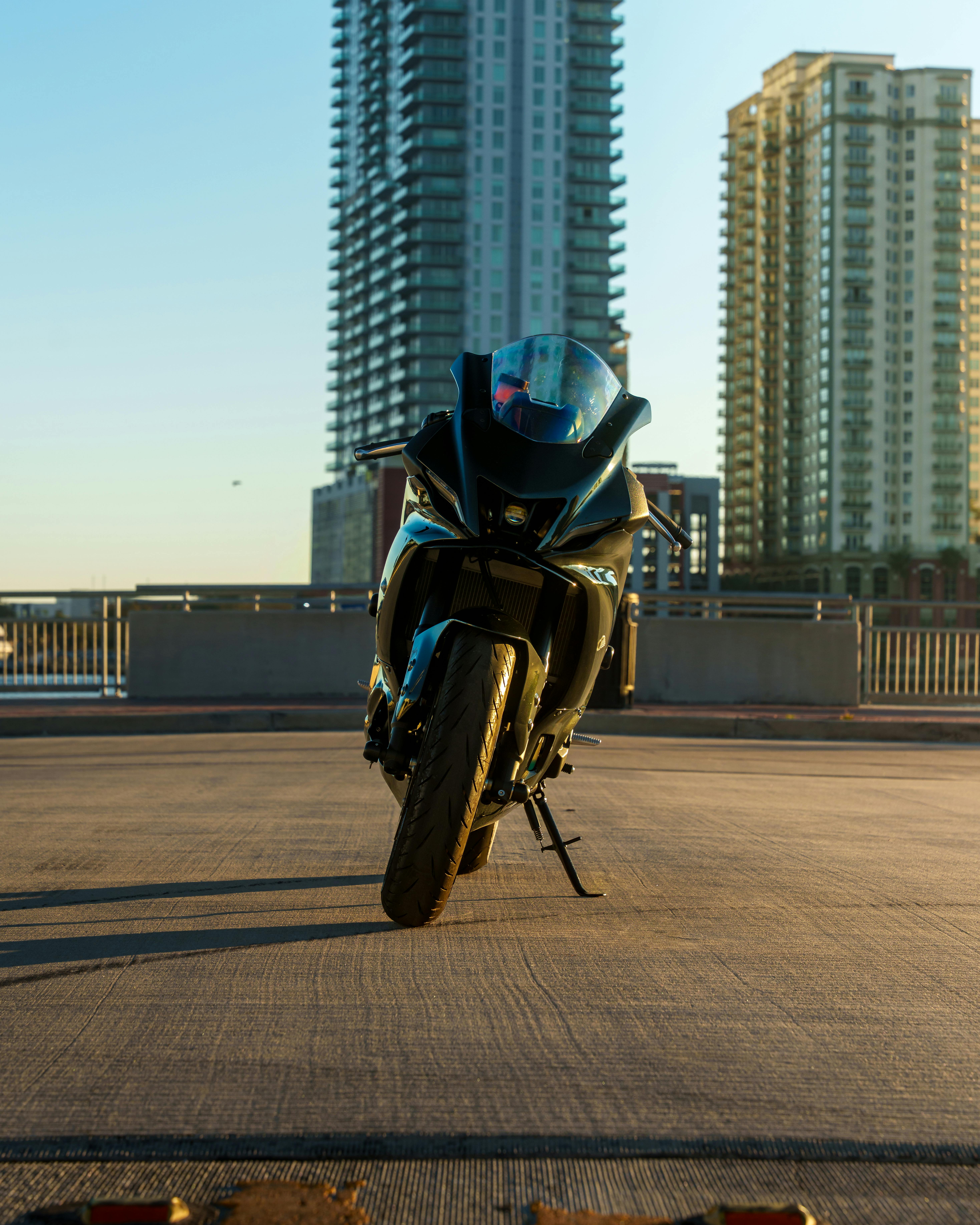 ฟรี รถจักรยานยนต์สุดหรูจอดอยู่หน้าตึกสูงระฟ้าในเมืองยามพระอาทิตย์ตกดิน แสดงให้เห็นถึงสไตล์แบบคนเมือง คลังภาพถ่าย