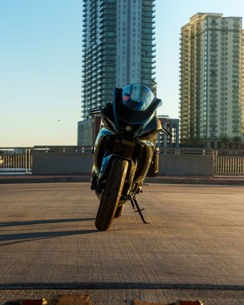 Free A sleek motorcycle parked in front of towering city buildings at sunset, showcasing urban style. Stock Photo
