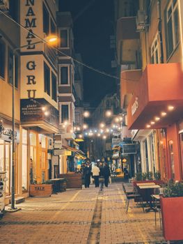 Nighttime street scene in Çanakkale, Türkiye with warm lights and vibrant atmosphere.