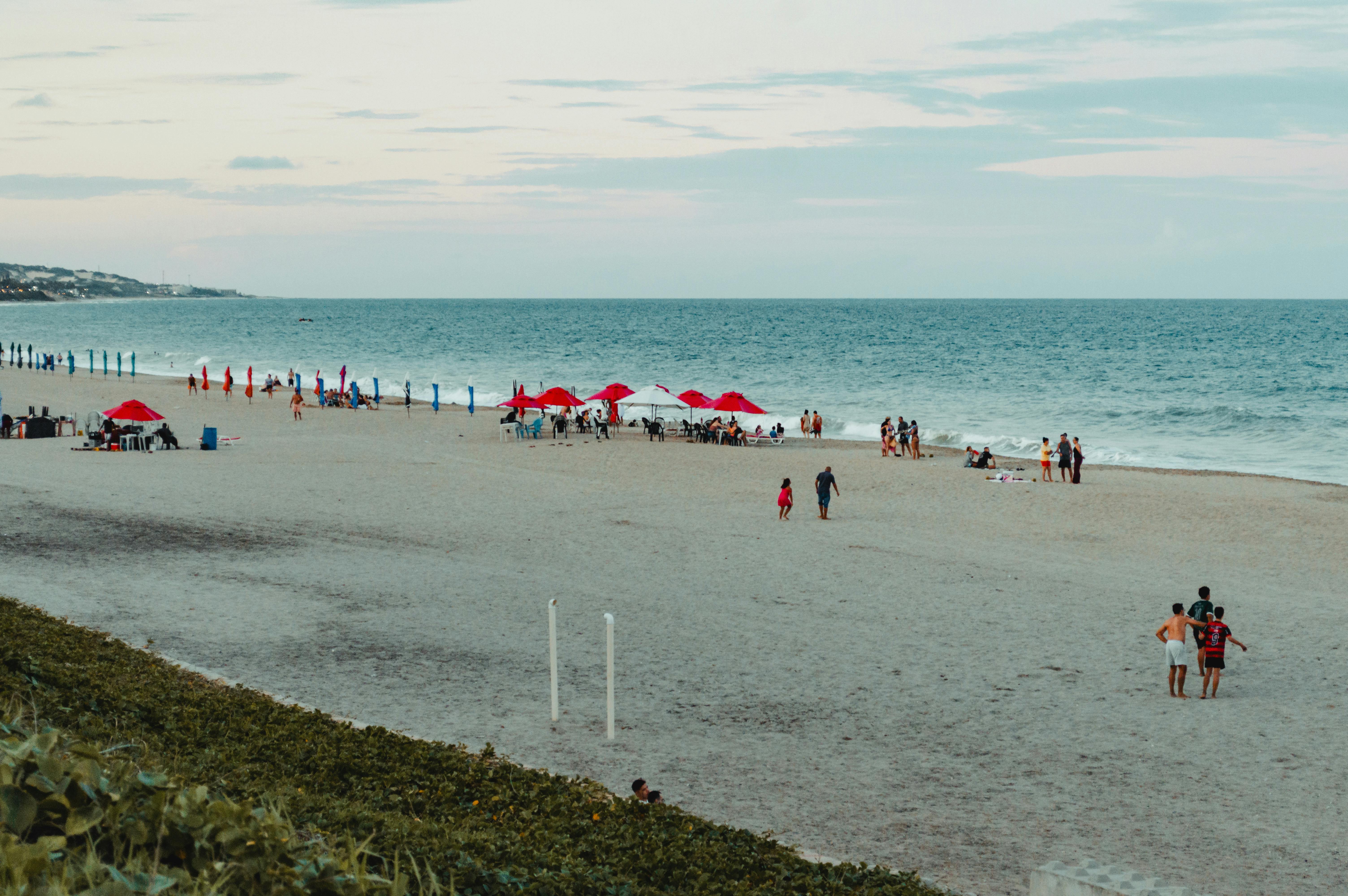 Beachgoers enjoy Ponta Negra in RN, Brazil with red umbrellas and serene ocean views.