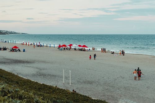 Free Beachgoers enjoy Ponta Negra in RN, Brazil with red umbrellas and serene ocean views. Stock Photo