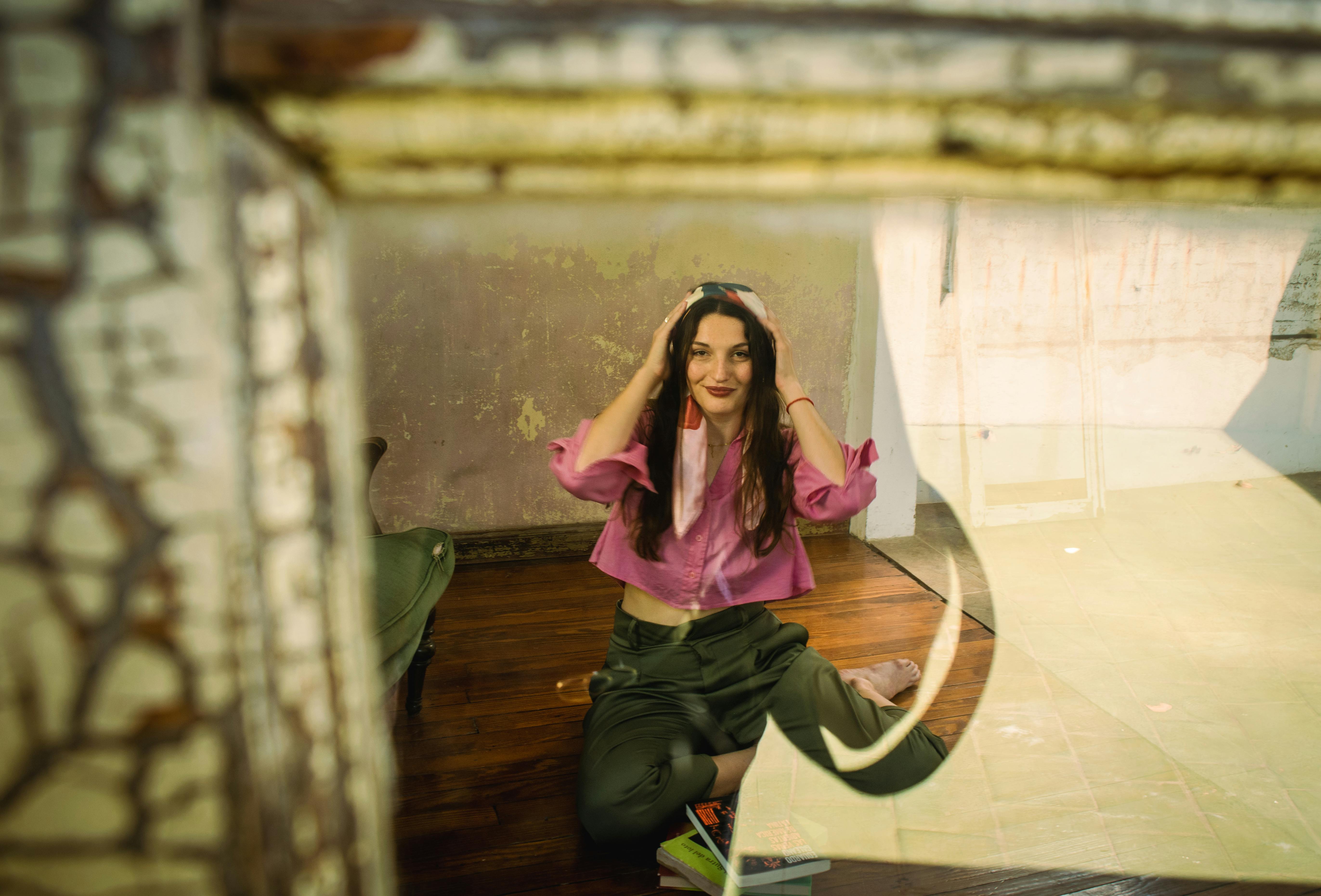 Gratis Giovane donna con un top rosa vista attraverso una finestra rustica, in un interno. Foto a disposizione