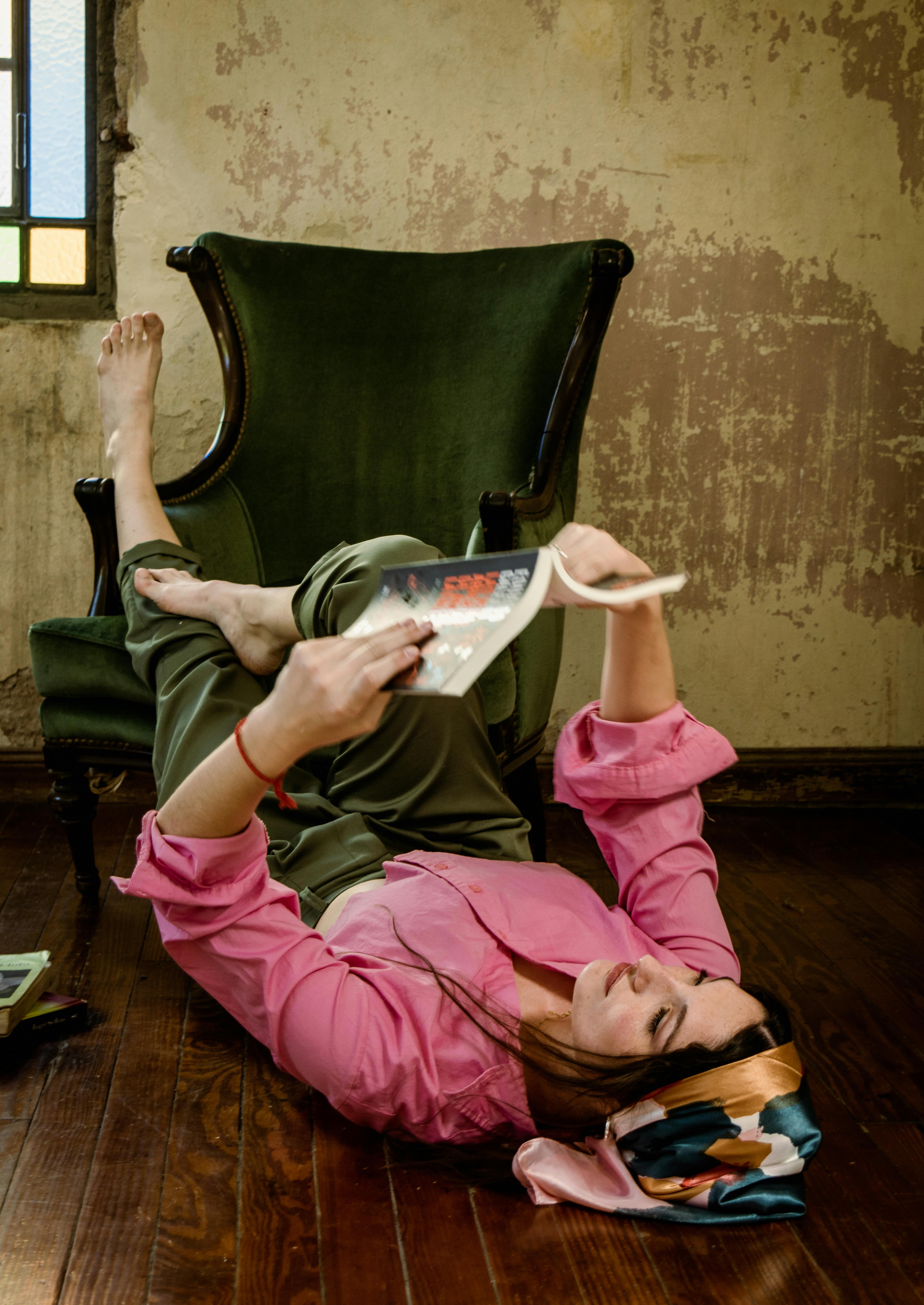 Gratis Una donna adulta sdraiata sul pavimento legge, creando un'atmosfera accogliente e rilassata all'interno. Foto a disposizione