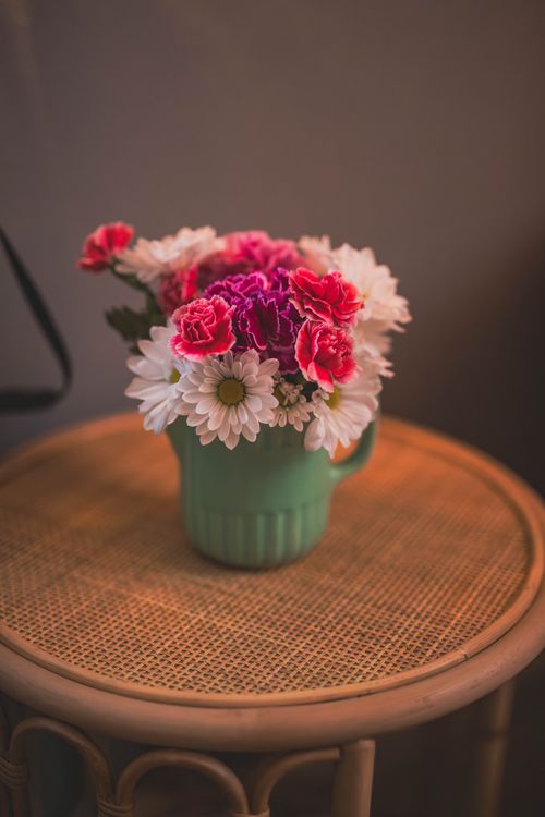 Free Charming floral arrangement with pink and white flowers in a green vase on a wicker table. Stock Photo