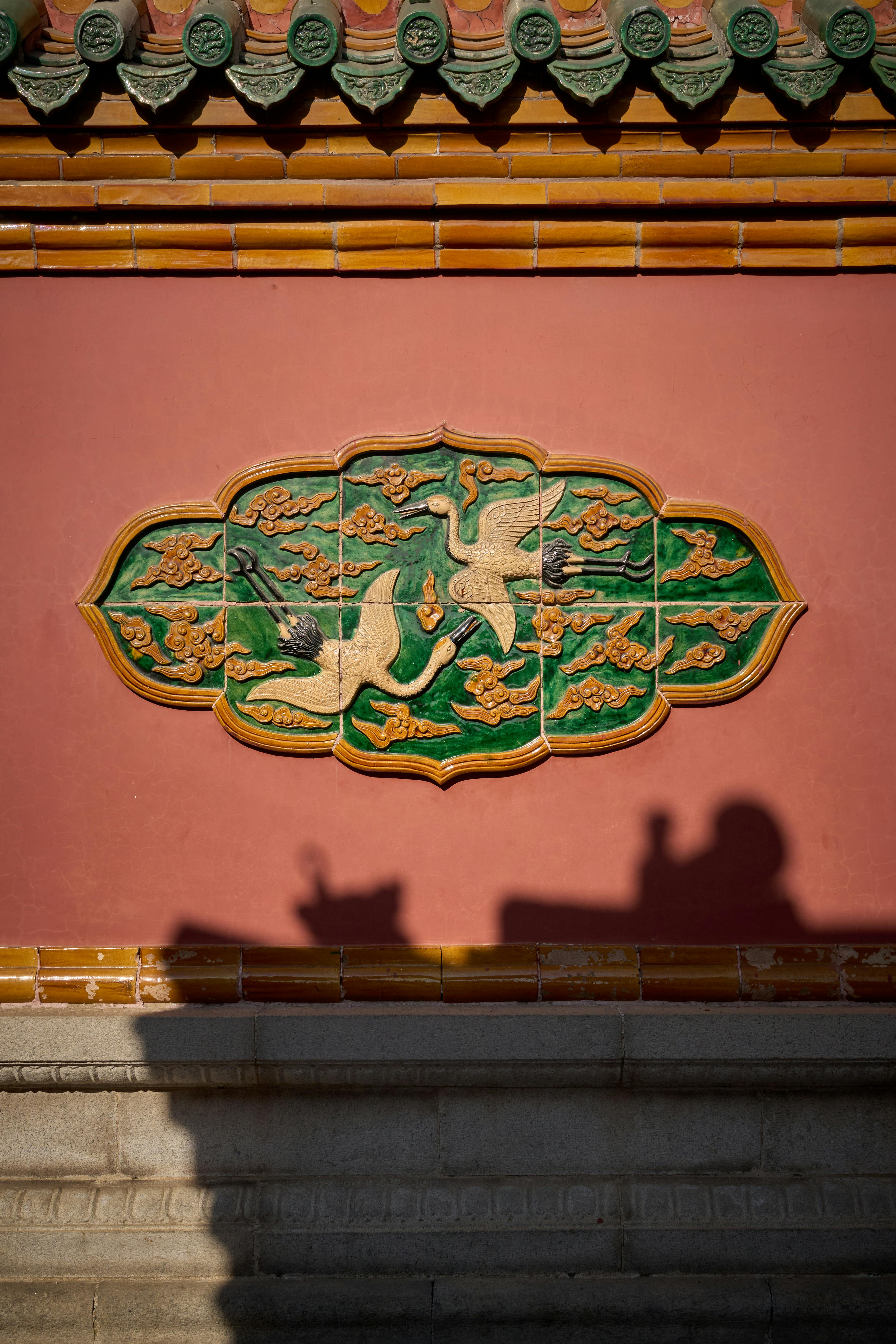 ฟรี ภาพระยะใกล้ของกระเบื้องตกแต่งแบบจีนดั้งเดิมบนผนังที่มีเงา ถ่ายกลางแจ้ง คลังภาพถ่าย