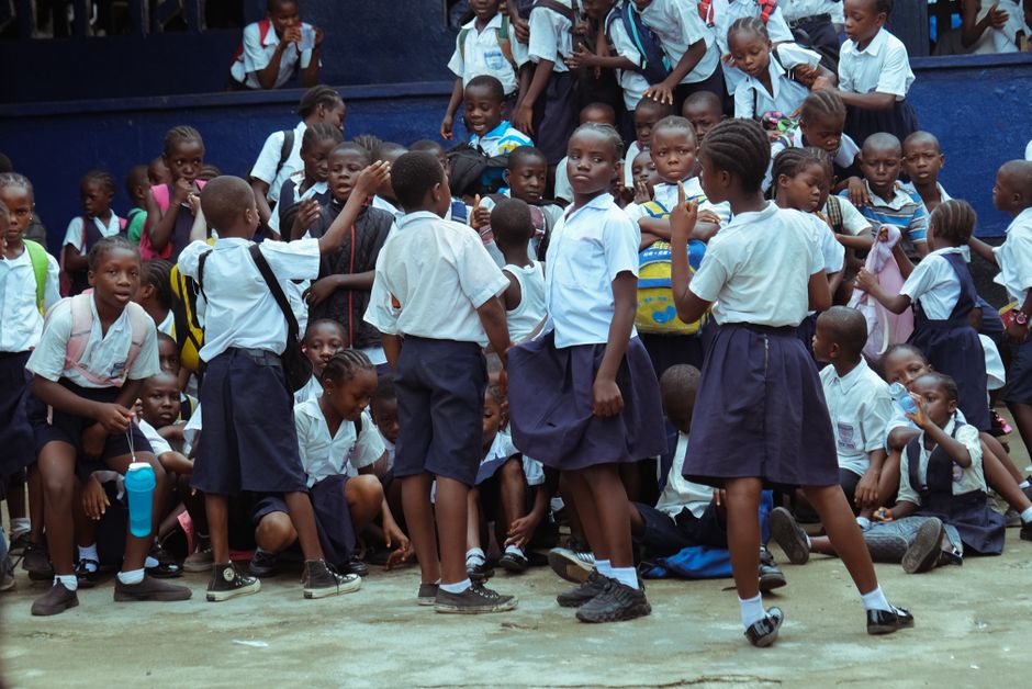 Group of schoolchildren in uniforms gathering together outside in Monrovia, Liberia.