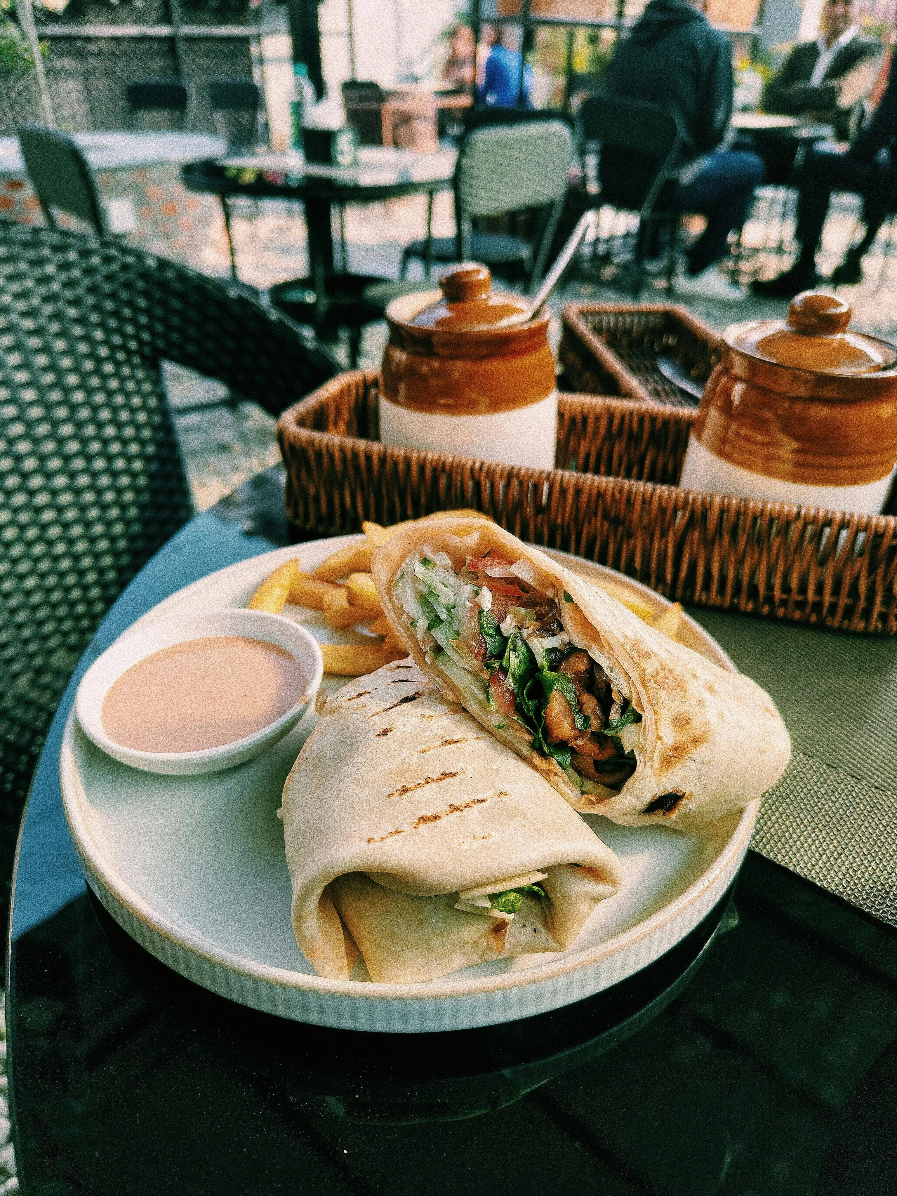 ฟรี แซนด์วิชห่อแสนอร่อย เสิร์ฟพร้อมเฟรนช์ฟรายส์และซอสบนโต๊ะอาหารในร้านอาหาร คลังภาพถ่าย