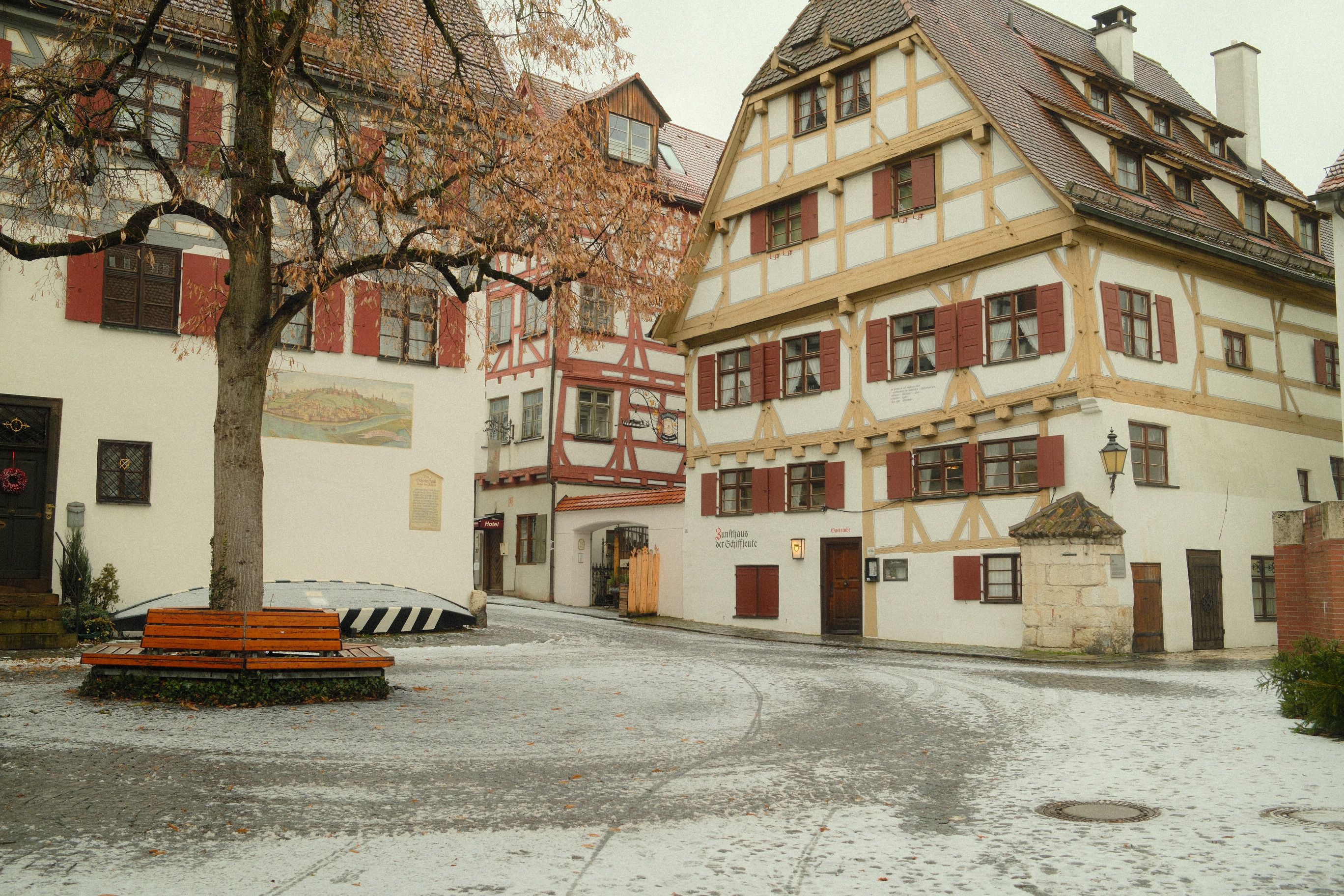 Charming Ulm street in winter featuring traditional half-timbered houses and a tree dusted with snow. - Ulm