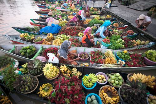 Free Colorful floating market scene with vendors in boats selling diverse fruits and vegetables. Stock Photo