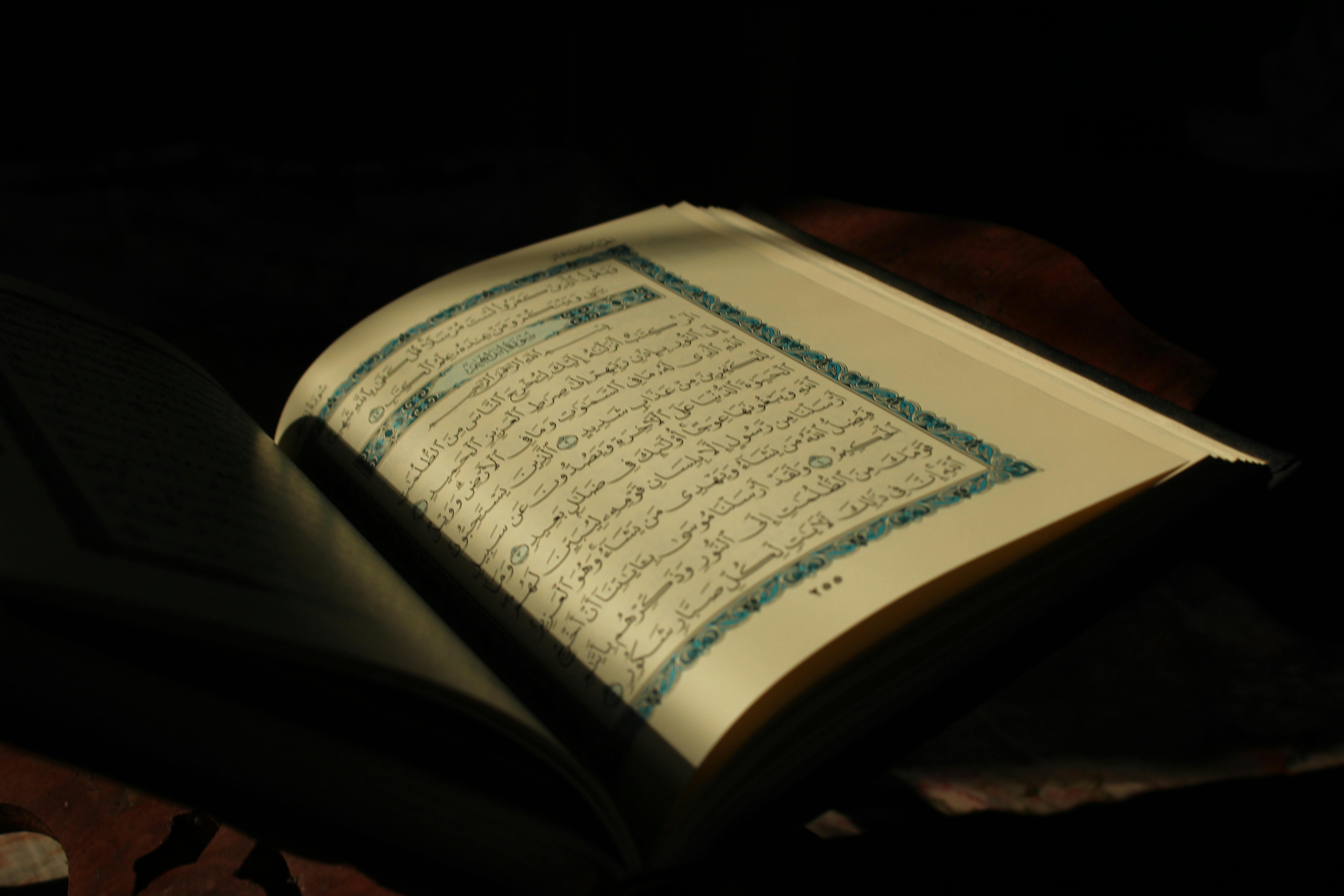 bezplatná Detail otevřené stránky Koránu osvětlené měkkým denním světlem, evokující odraz. Základová fotografie