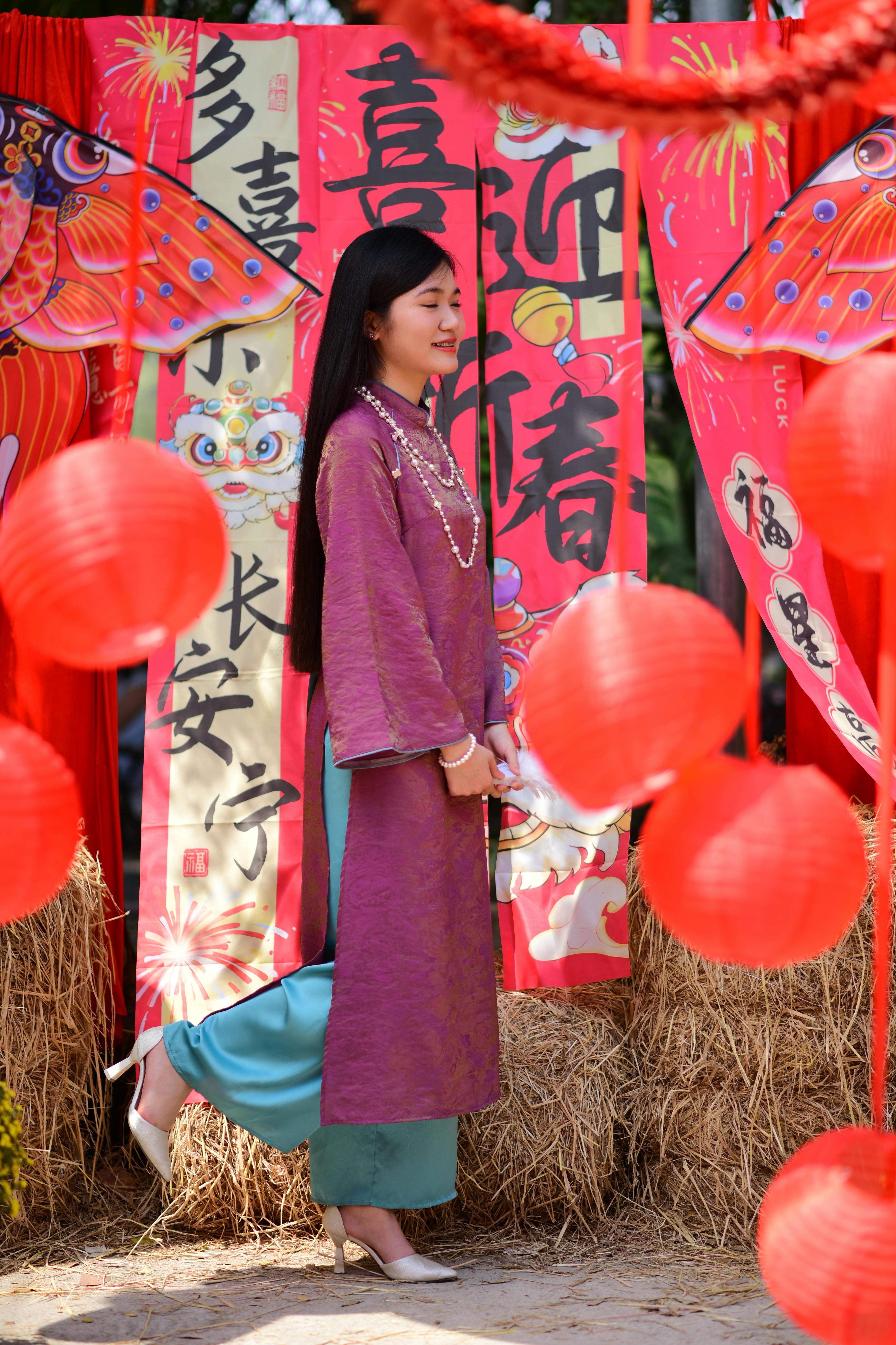 ฟรี หญิงสาวในชุดพื้นเมืองกำลังเฉลิมฉลองเทศกาลเอเชียด้วยโคมไฟสีแดงและการเขียนอักษรจีน คลังภาพถ่าย