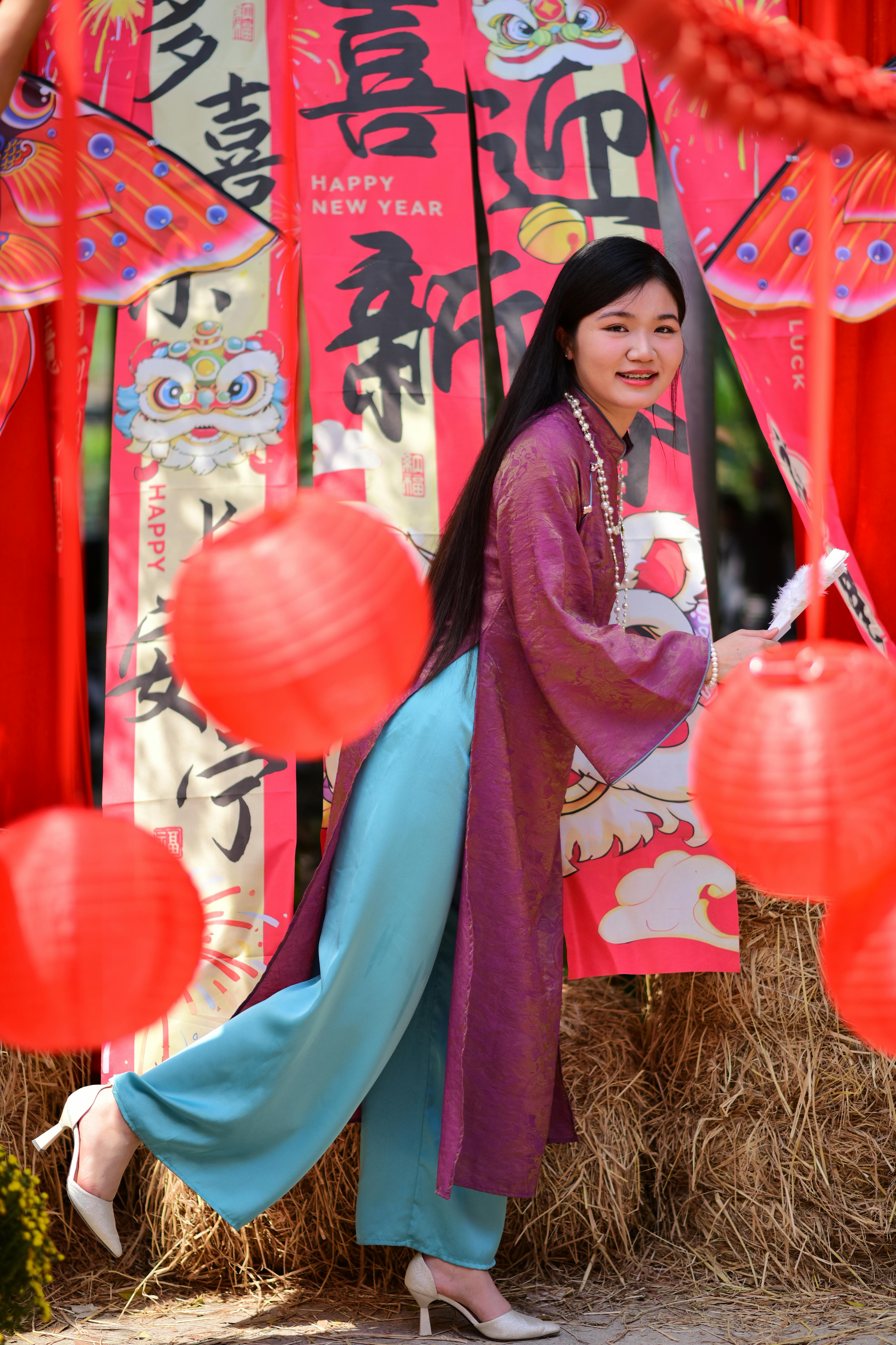 ฟรี หญิงสาวในชุดพื้นเมืองกำลังเฉลิมฉลองเทศกาลตรุษจีนด้วยเครื่องประดับหลากสีสันอย่างมีความสุข คลังภาพถ่าย