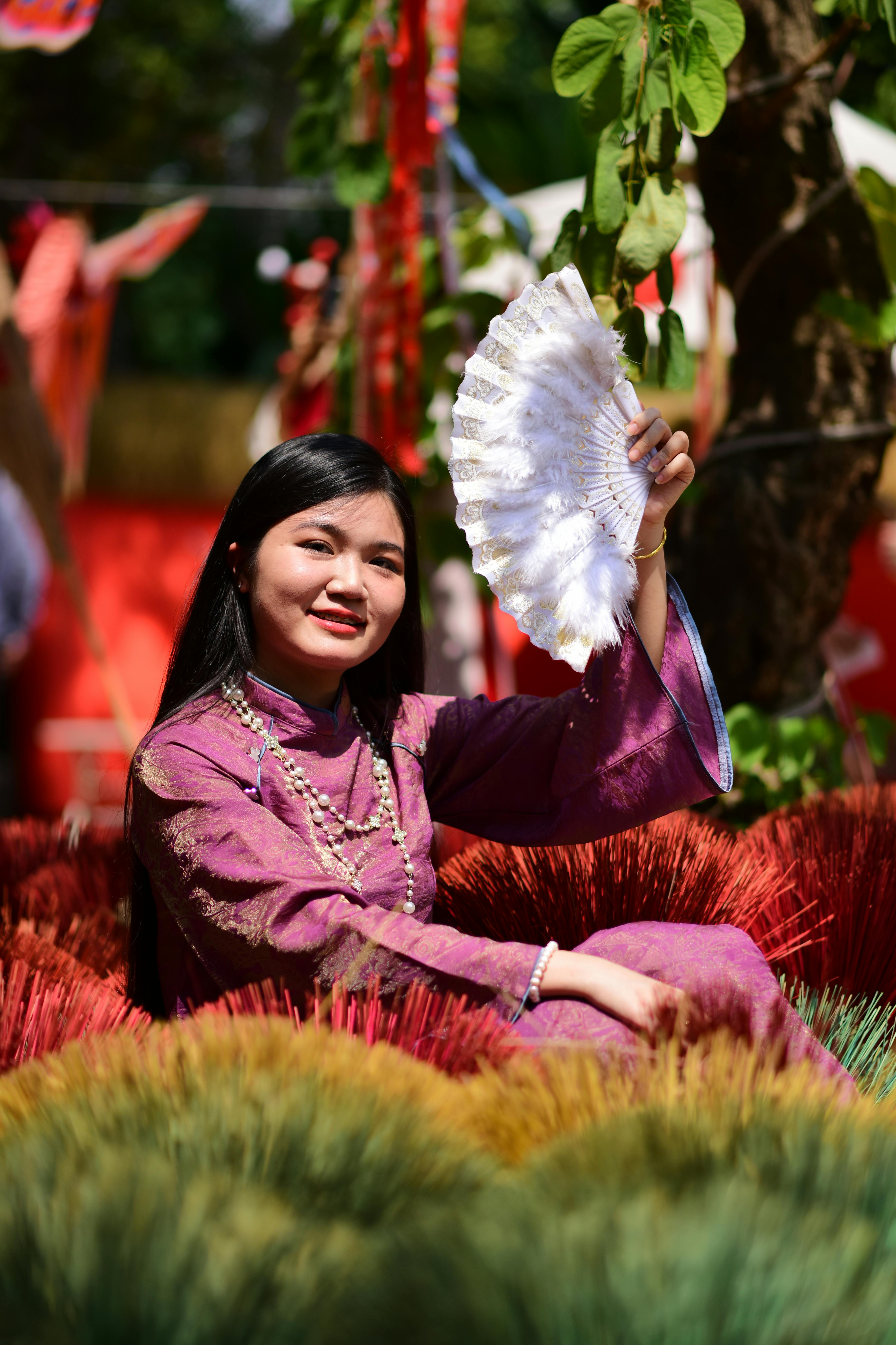 ฟรี ภาพวาดหญิงสาวในชุดพื้นเมืองถือพัด ท่ามกลางสีสันสดใส คลังภาพถ่าย