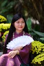 Woman in Traditional Outfit with Fan Amidst Flowers