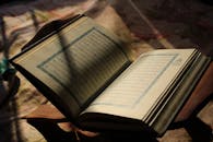 Open Quran in sunlight on wooden stand