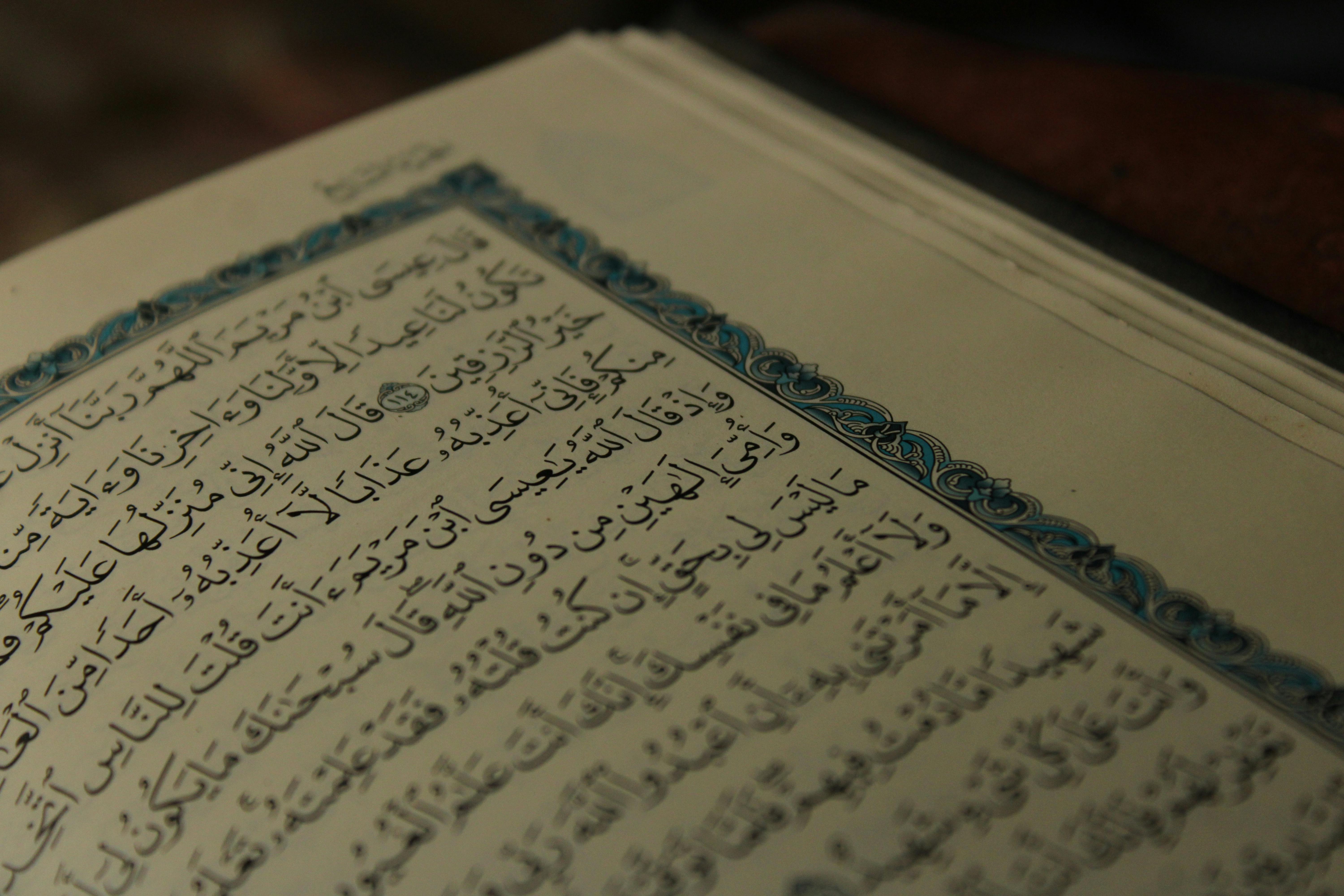 Intricate Arabic calligraphy on an open page of a religious book, showcasing artistic detail.
