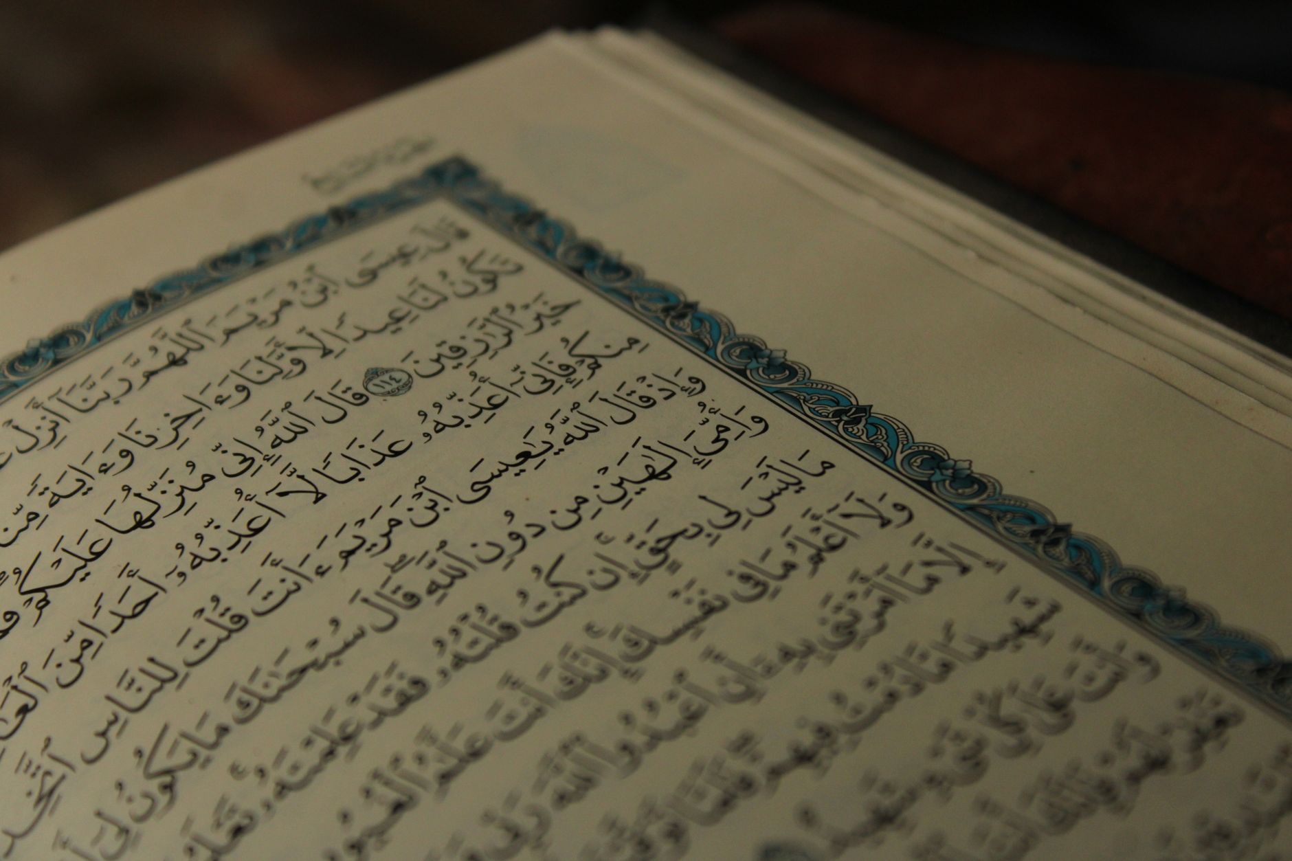 Intricate Arabic calligraphy on an open page of a religious book, showcasing artistic detail.