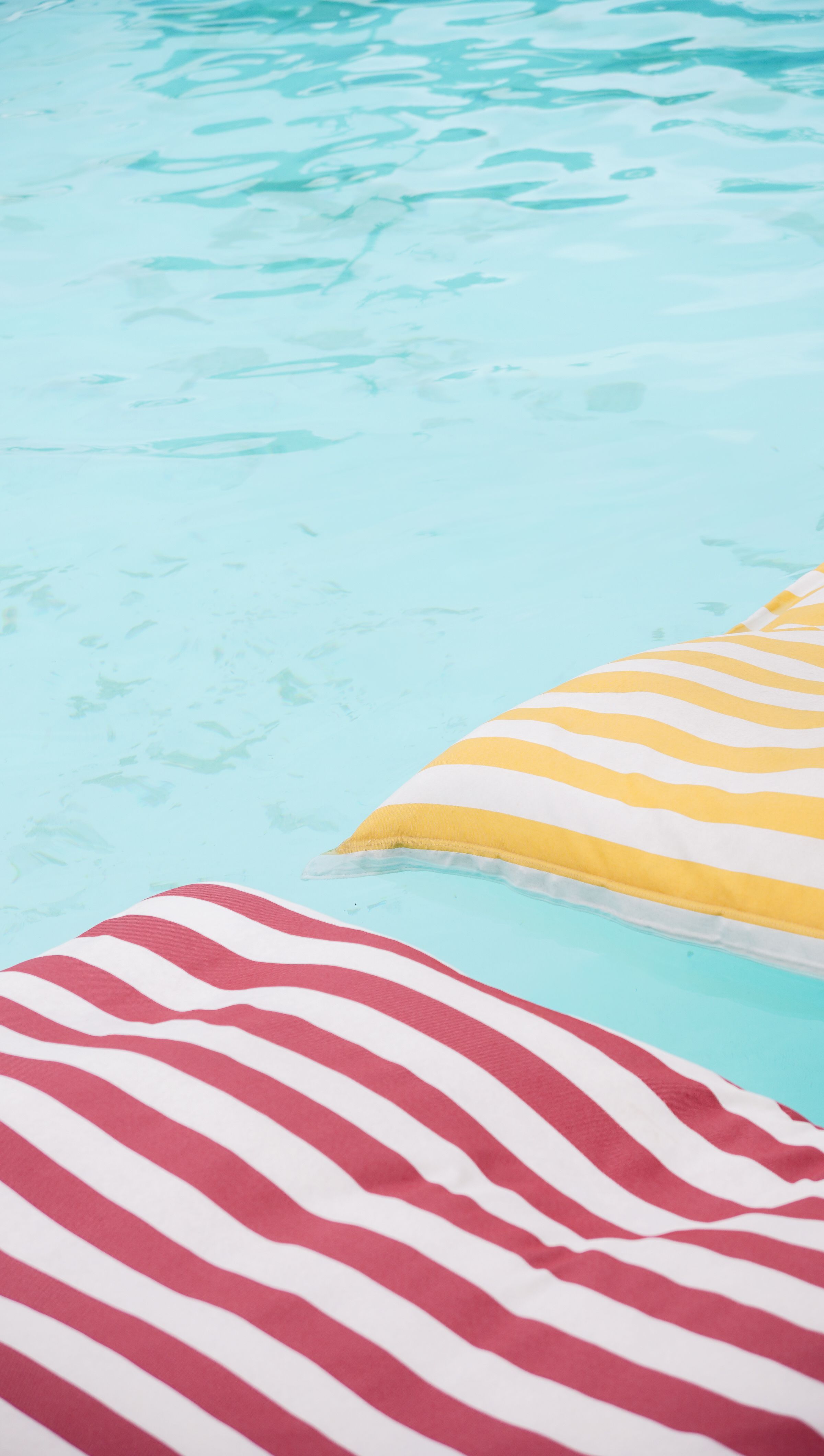 Vibrant striped pool floats on refreshing clear water, perfect for summer relaxation.