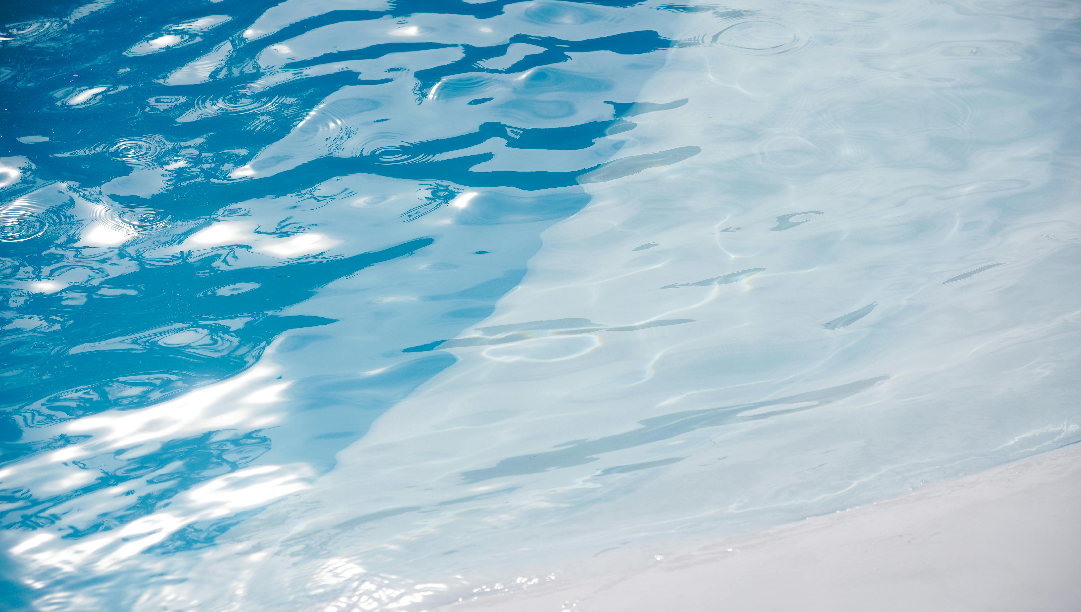 Glistening blue pool water with sunlit ripples creating a serene and refreshing ambiance.