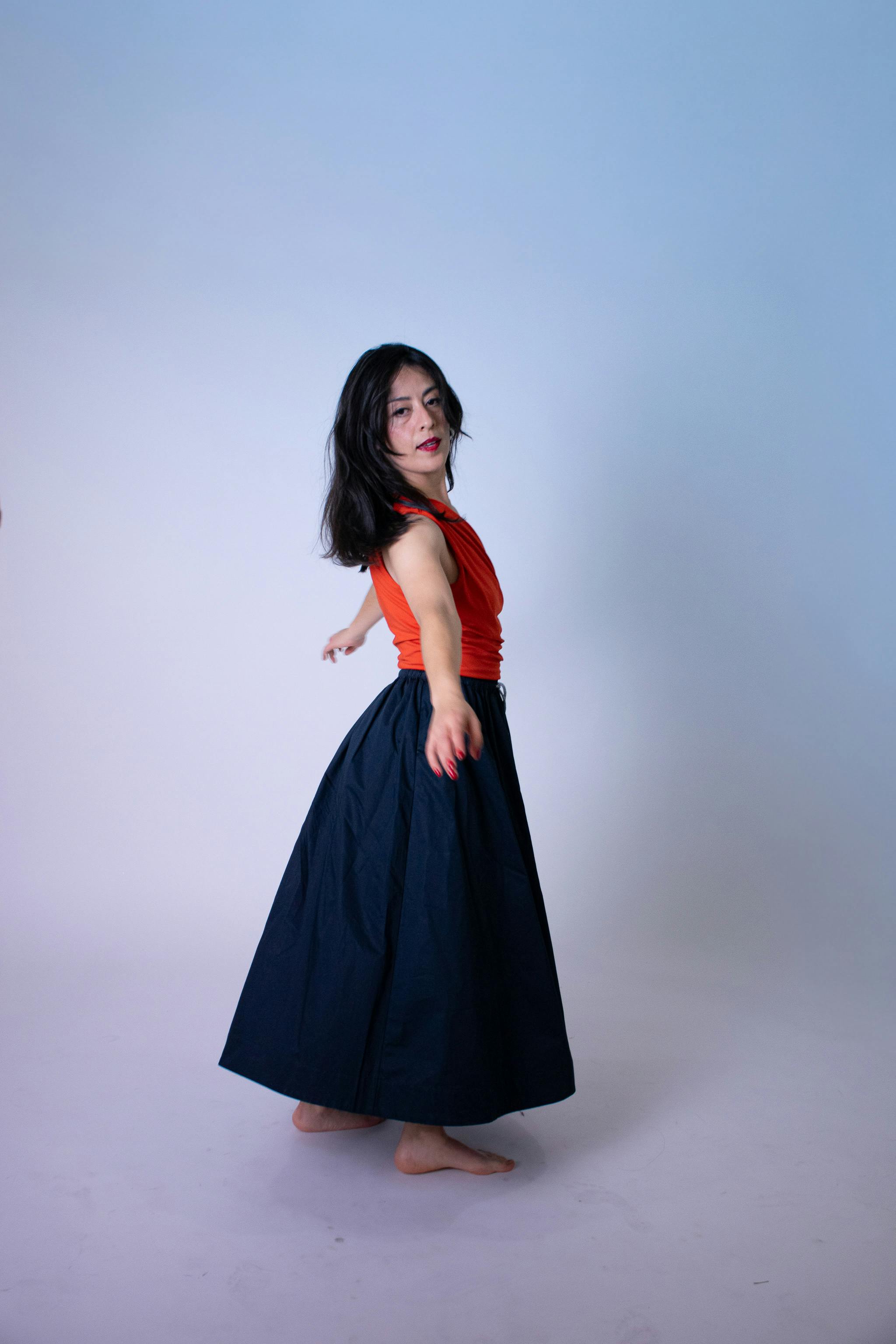 Gratis Elegante ritratto di una donna che balla con un abito vivace su uno sfondo semplice. Foto a disposizione