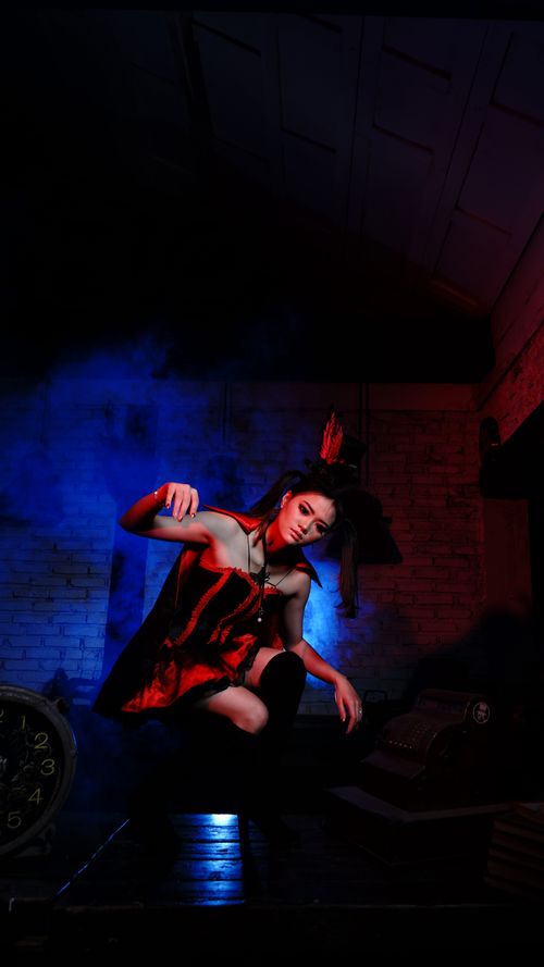 Free Striking portrait of a woman in a red dress with dramatic lighting and blue smoke effect. Stock Photo