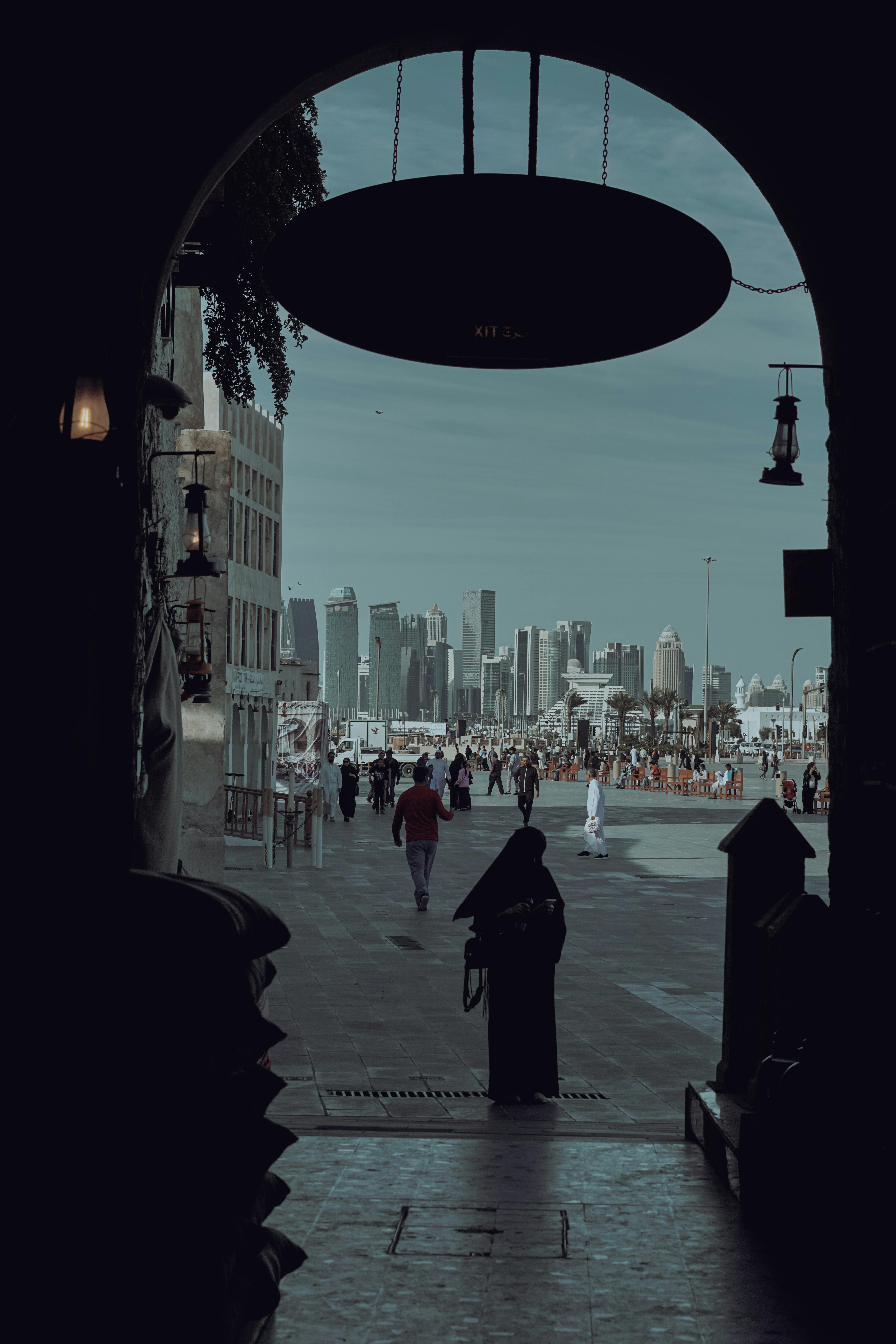 Ücretsiz Modern ve geleneksel unsurları bir araya getiren tarihi bir kemer geçidinden Doha'nın silüetine bir bakış. Stok Fotoğraflar