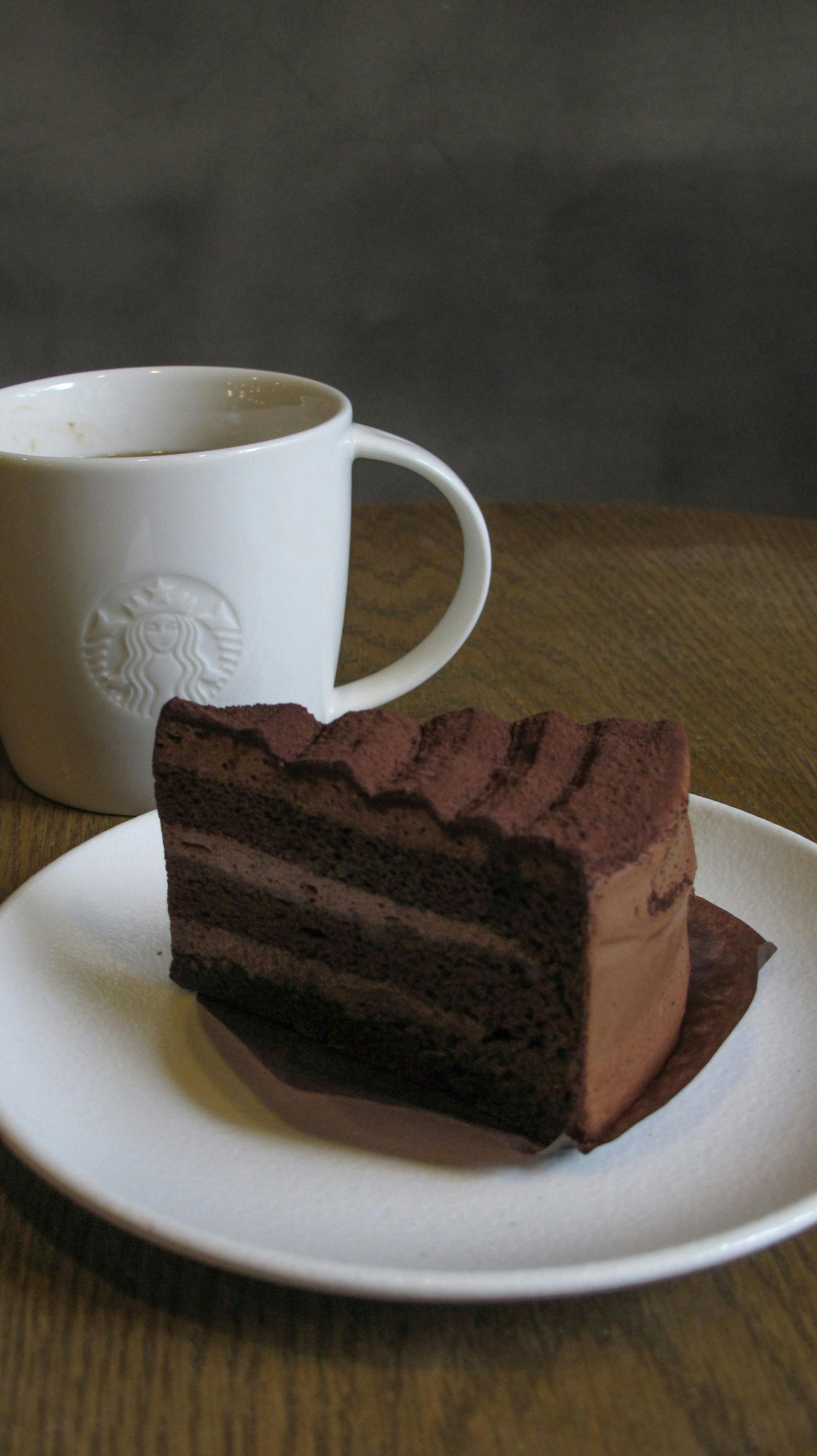 bezplatná Lahodný kousek čokoládového dortu elegantně sladěný s šálkem horké kávy, ideální pro milovníky dezertů. Základová fotografie