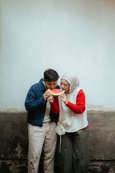 Happy couple in casual attire sharing a watermelon outdoors in Indonesia. - Fotografer Sidoarjo