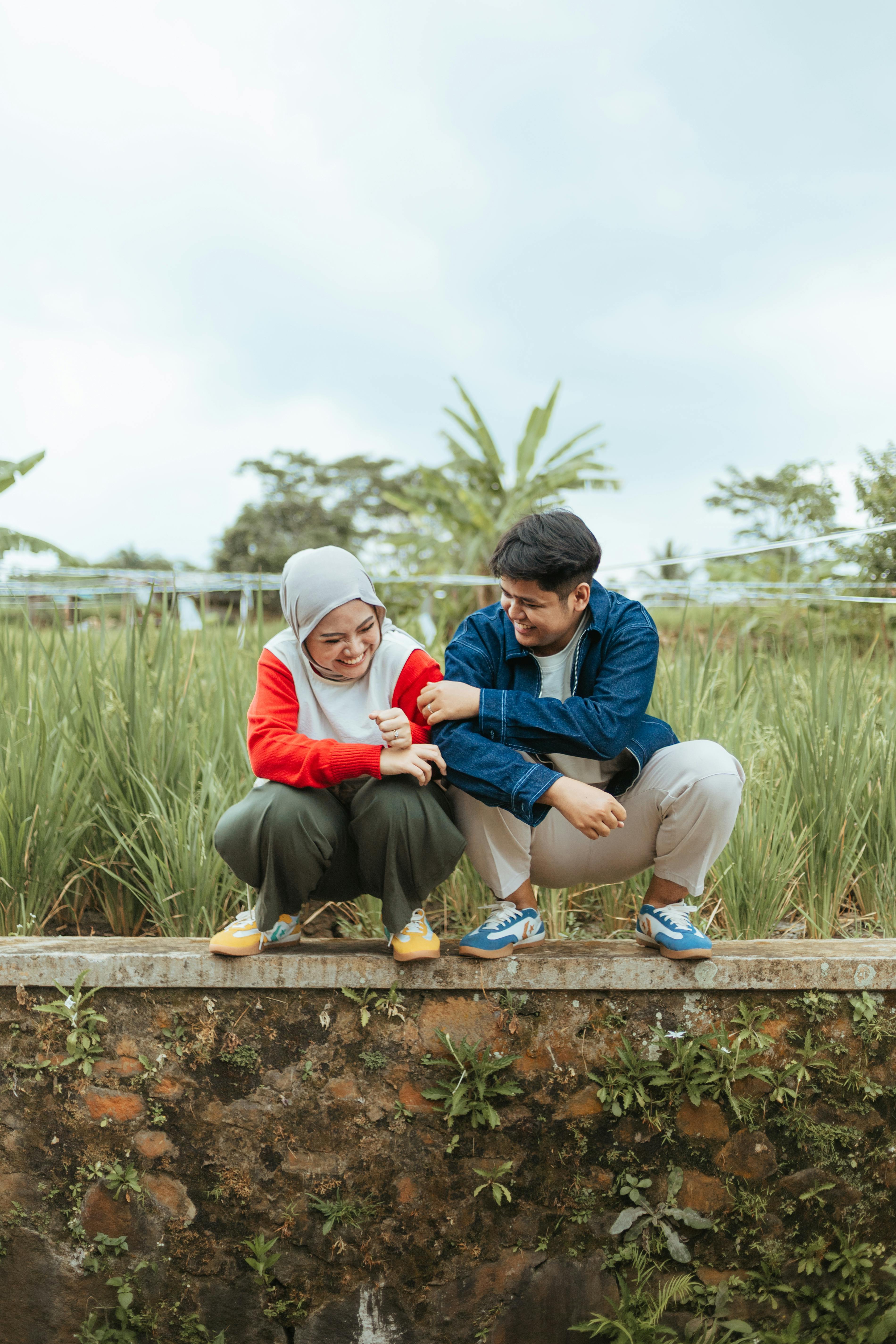 Ilmainen Onnellinen pari ulkona Indonesiassa, istumassa pellolla ja nauttimassa toistensa seurasta. Kuvapankkikuva