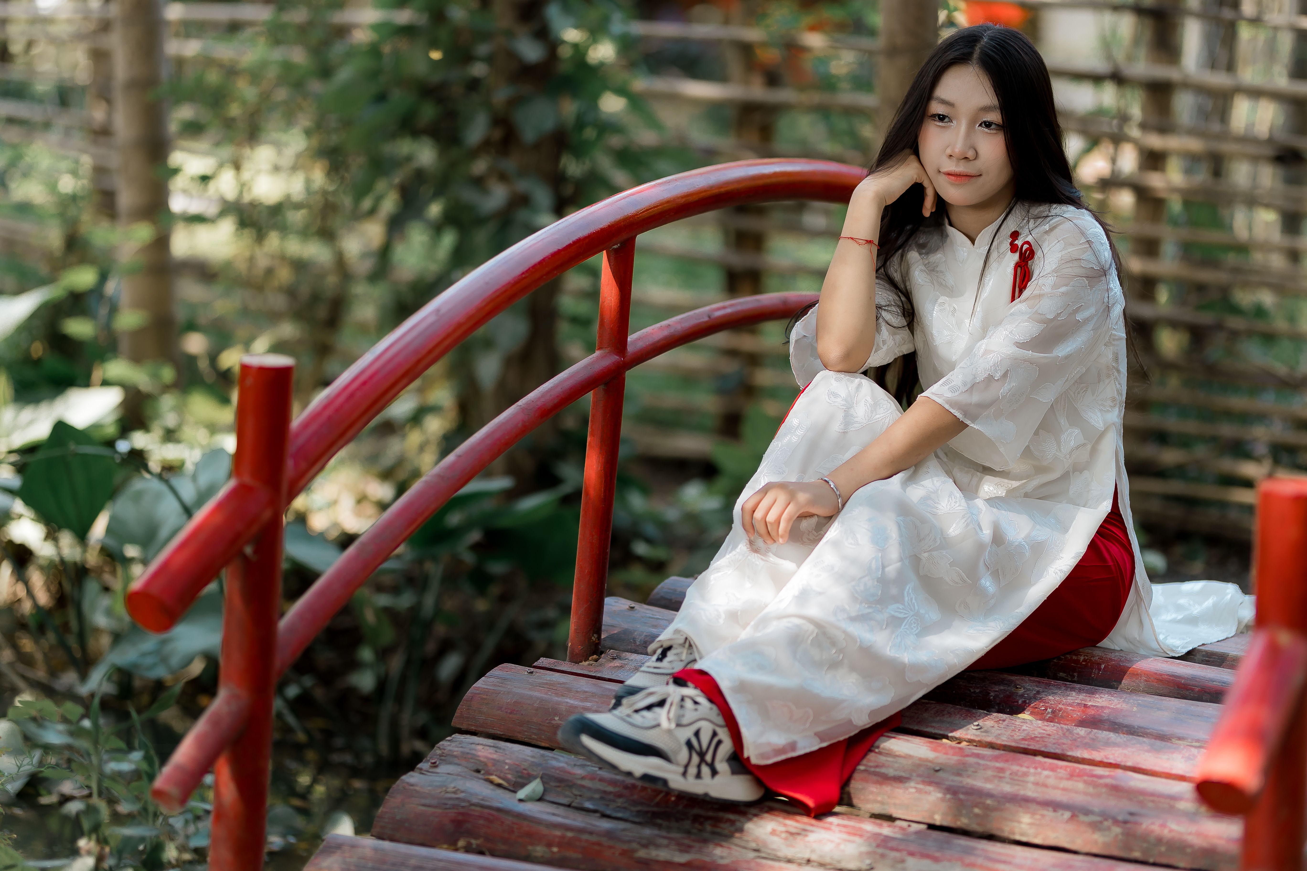 Young Woman in Traditional Dress on Red Bridge Outdoors · Free Stock Photo