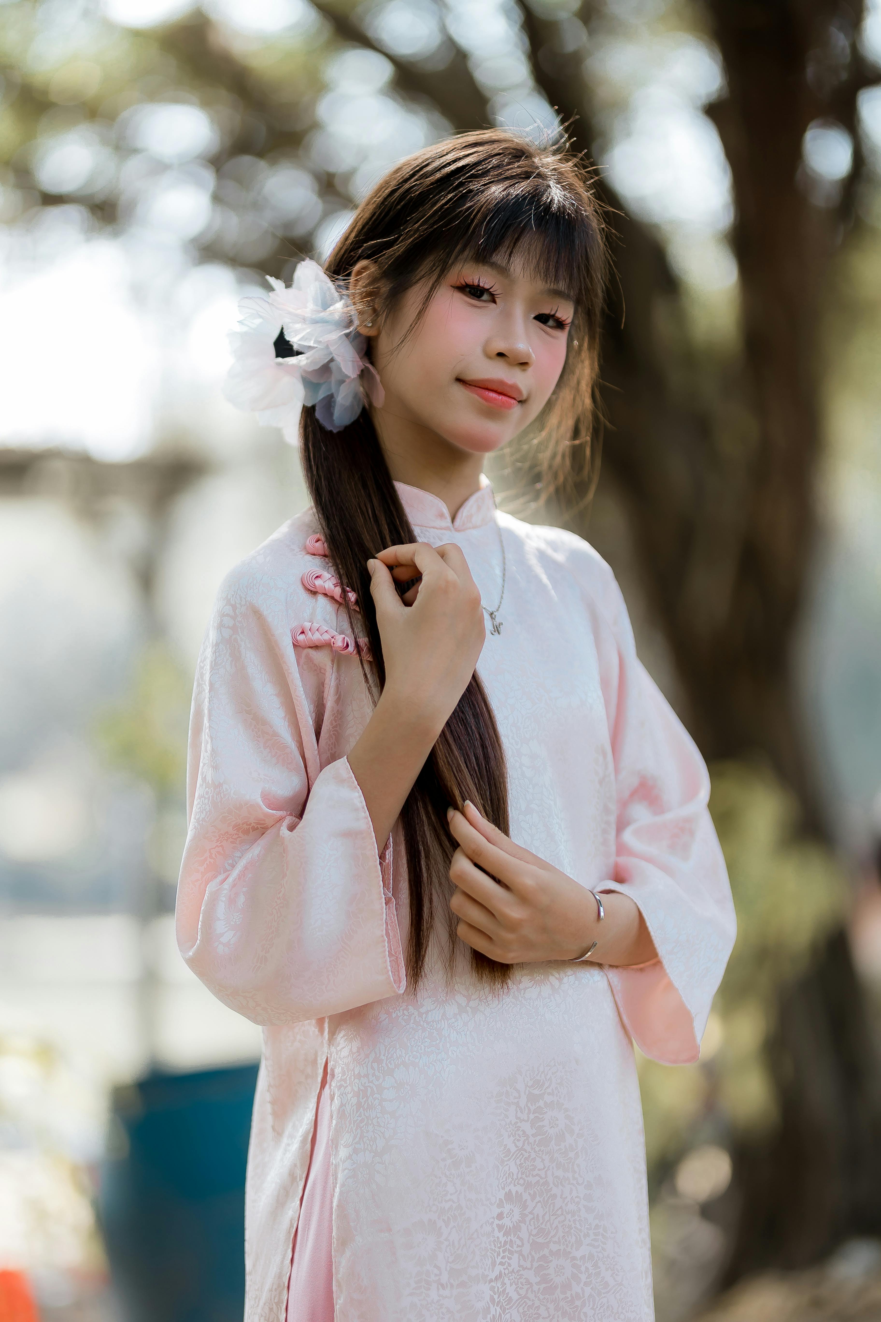 Gratis Ritratto di una giovane donna in abito tradizionale rosa, in piedi all'aperto, con luci soffuse. Foto a disposizione