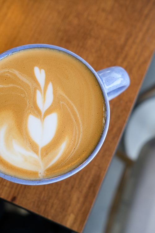 Free Elegant latte with art in a blue cup on a wooden table, top view. Stock Photo
