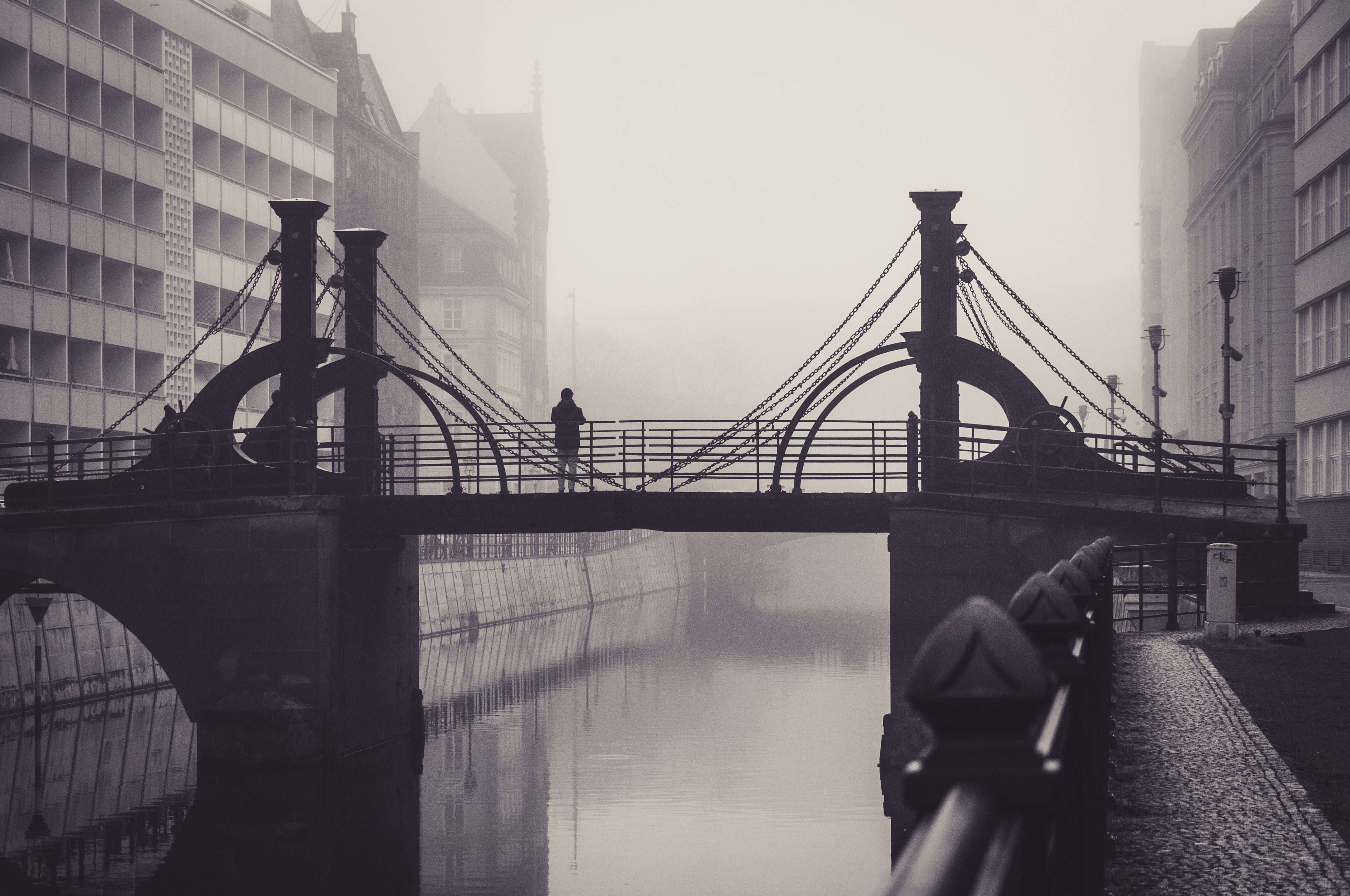 Puente urbano cubierto de niebla con una figura al fondo: metáfora de sostén, continuidad y estabilidad