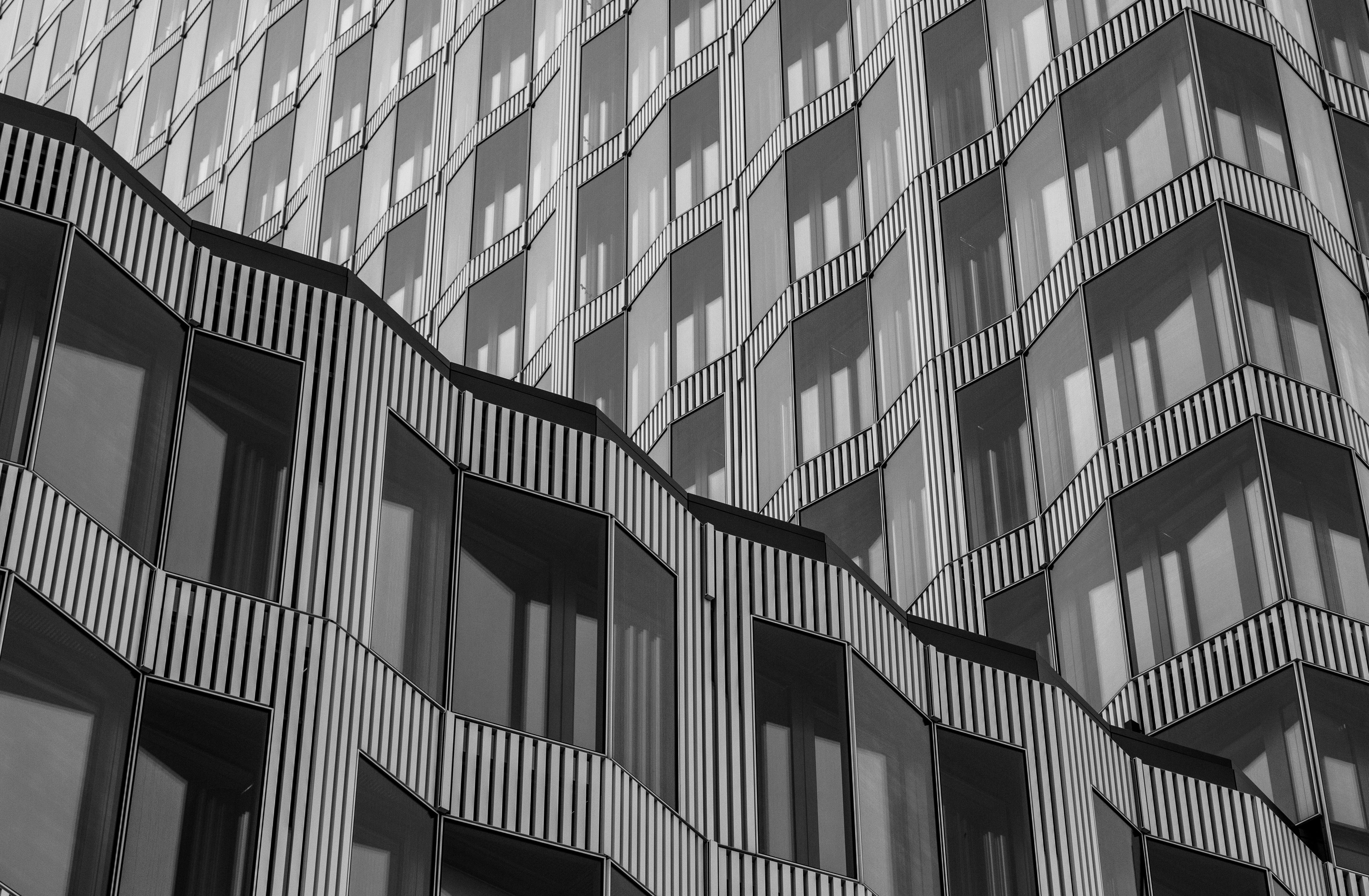 Ilmainen Modernin rakennuksen julkisivu aaltoilevine linjoineen ja geometrisine kuvioineen mustavalkoisessa valokuvassa. Kuvapankkikuva