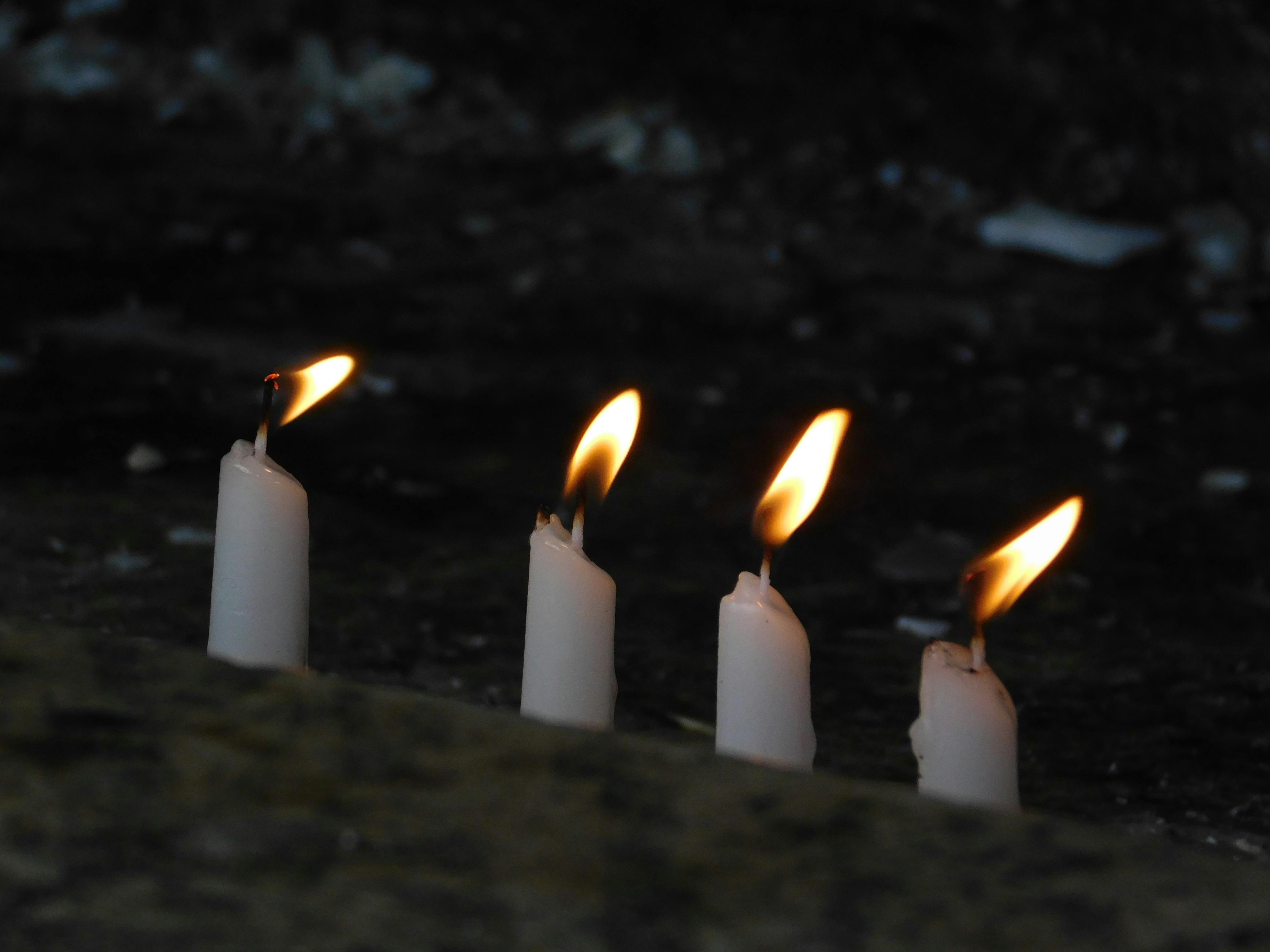 bezplatná Čtyři zářící svíčky vytvářejí v tlumeném osvětlení klidnou atmosféru. Základová fotografie