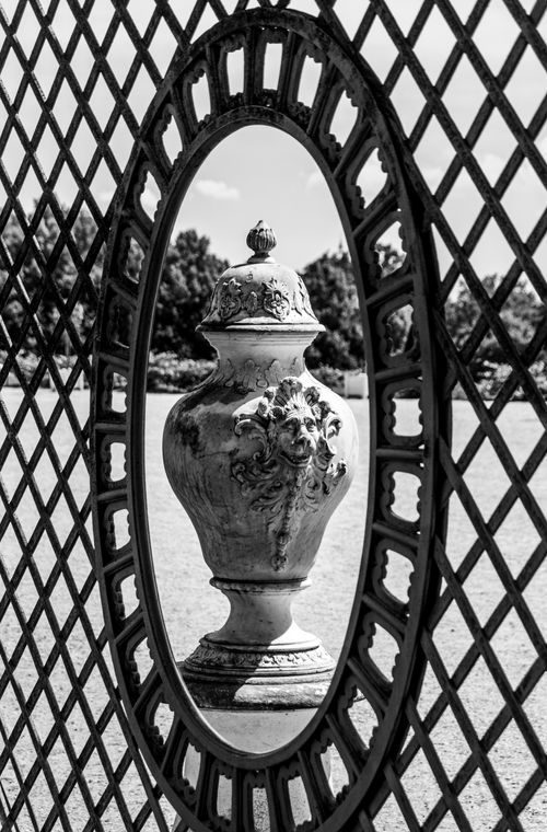 Free A classical garden urn is beautifully framed within an ornate lattice mirror in this artistic black and white composition. Stock Photo
