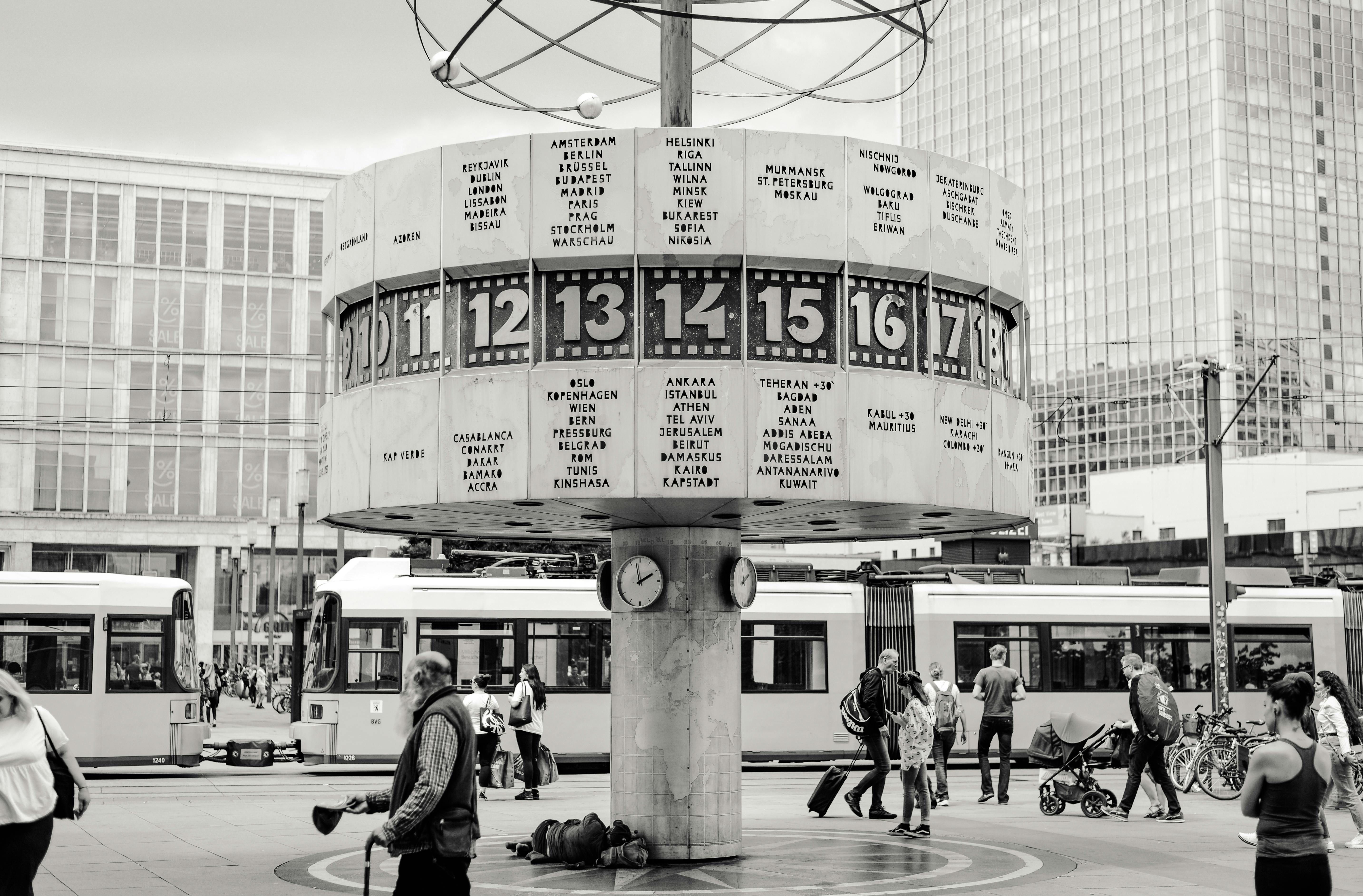 Gratis Svart-hvitt-bilde av verdensklokken på Alexanderplatz i Berlin, et yrende folkemengde og trikker. Arkivbilde