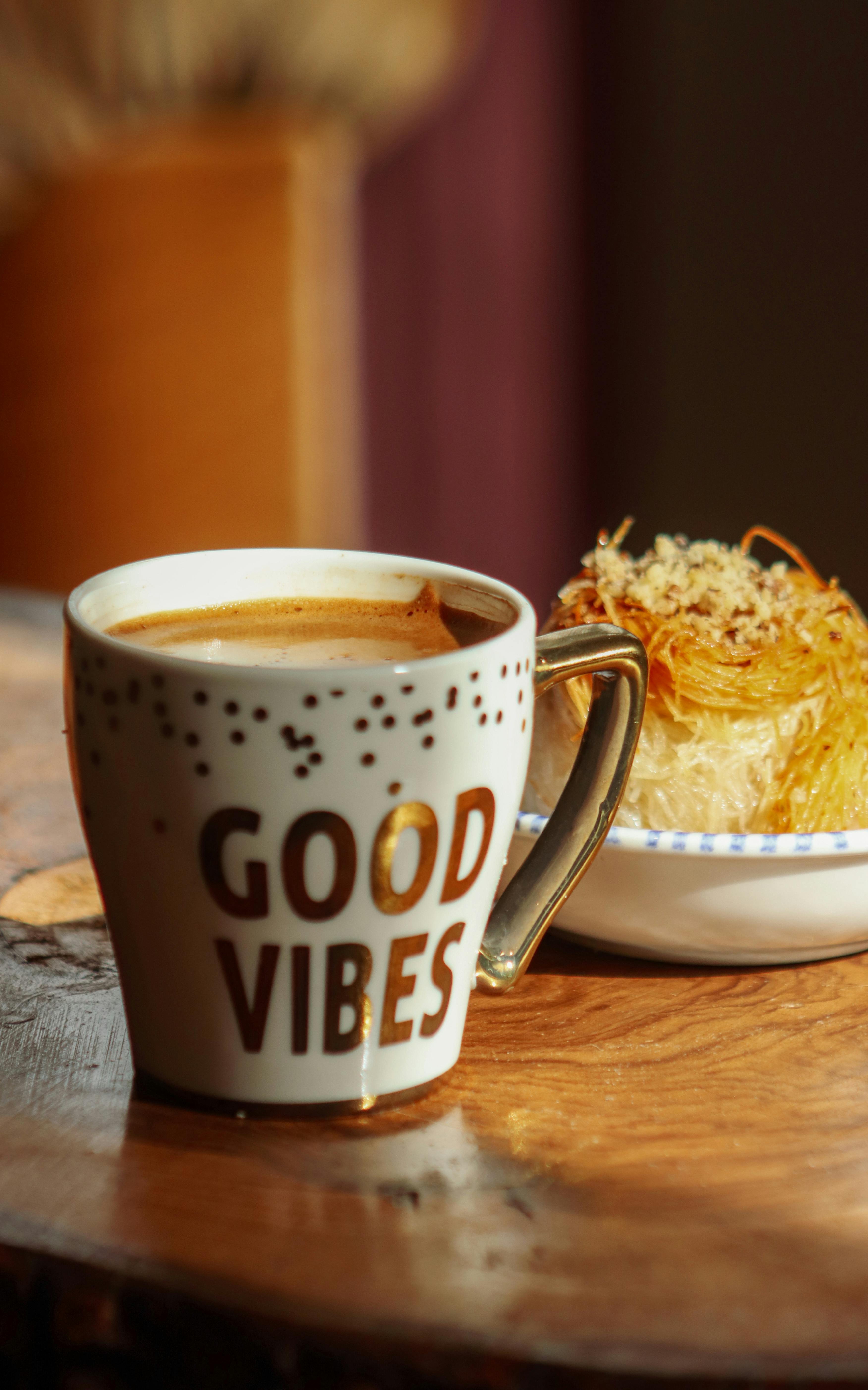 A cozy coffee cup with 'Good Vibes' and a delicious pastry on a wooden table.