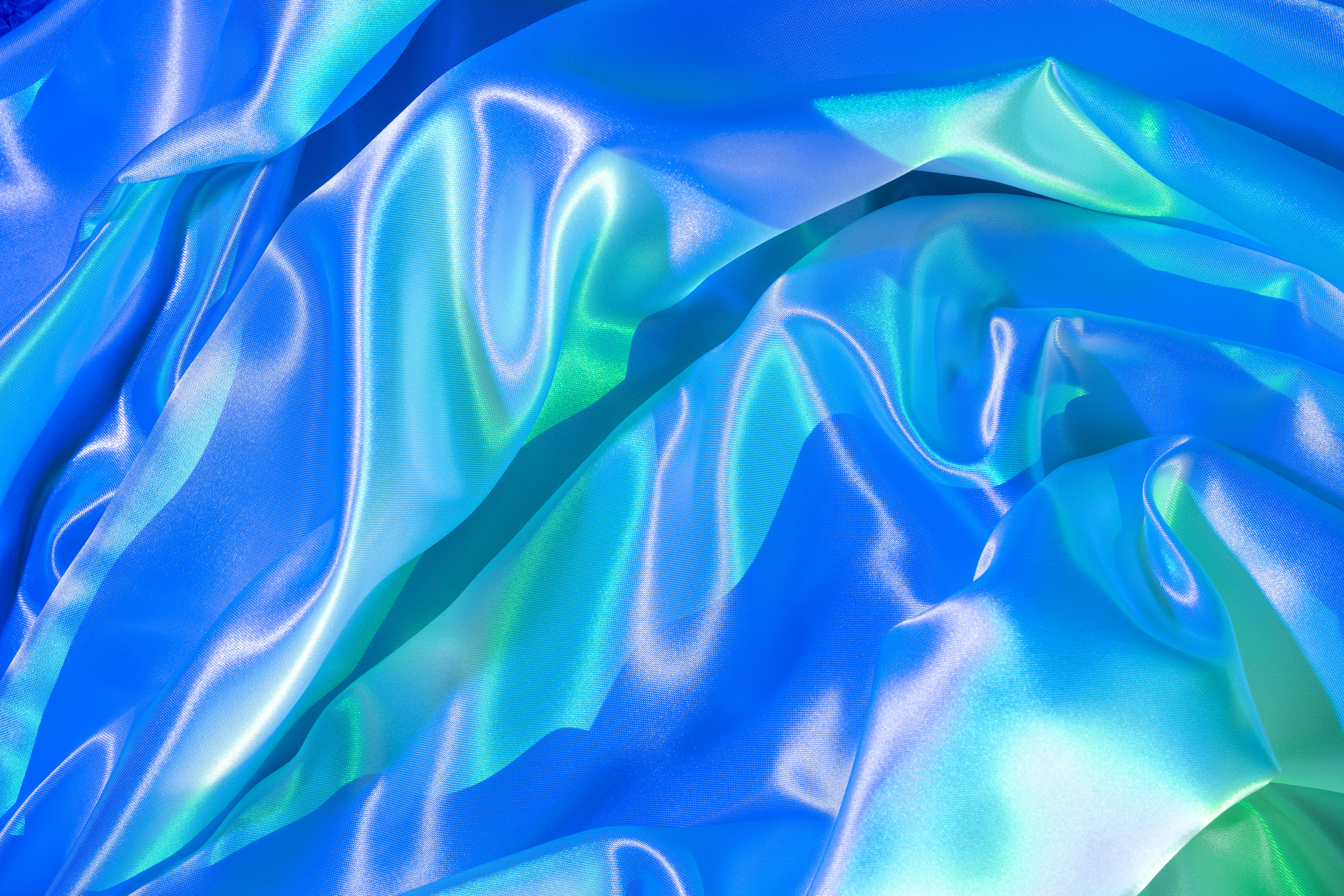Gratis Primo piano di un vivace tessuto di seta satinata con eleganti riflessi blu e verdi, che creano una lussuosa texture astratta. Foto a disposizione