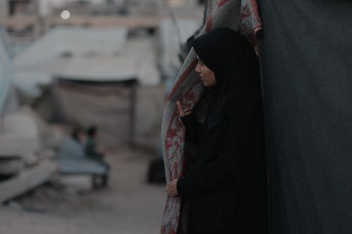 Free A contemplative woman in traditional attire stands amidst Gaza's urban landscape. Stock Photo