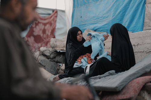 Free A mother tends to her child in Gaza amidst the backdrop of conflict and resilience. Stock Photo