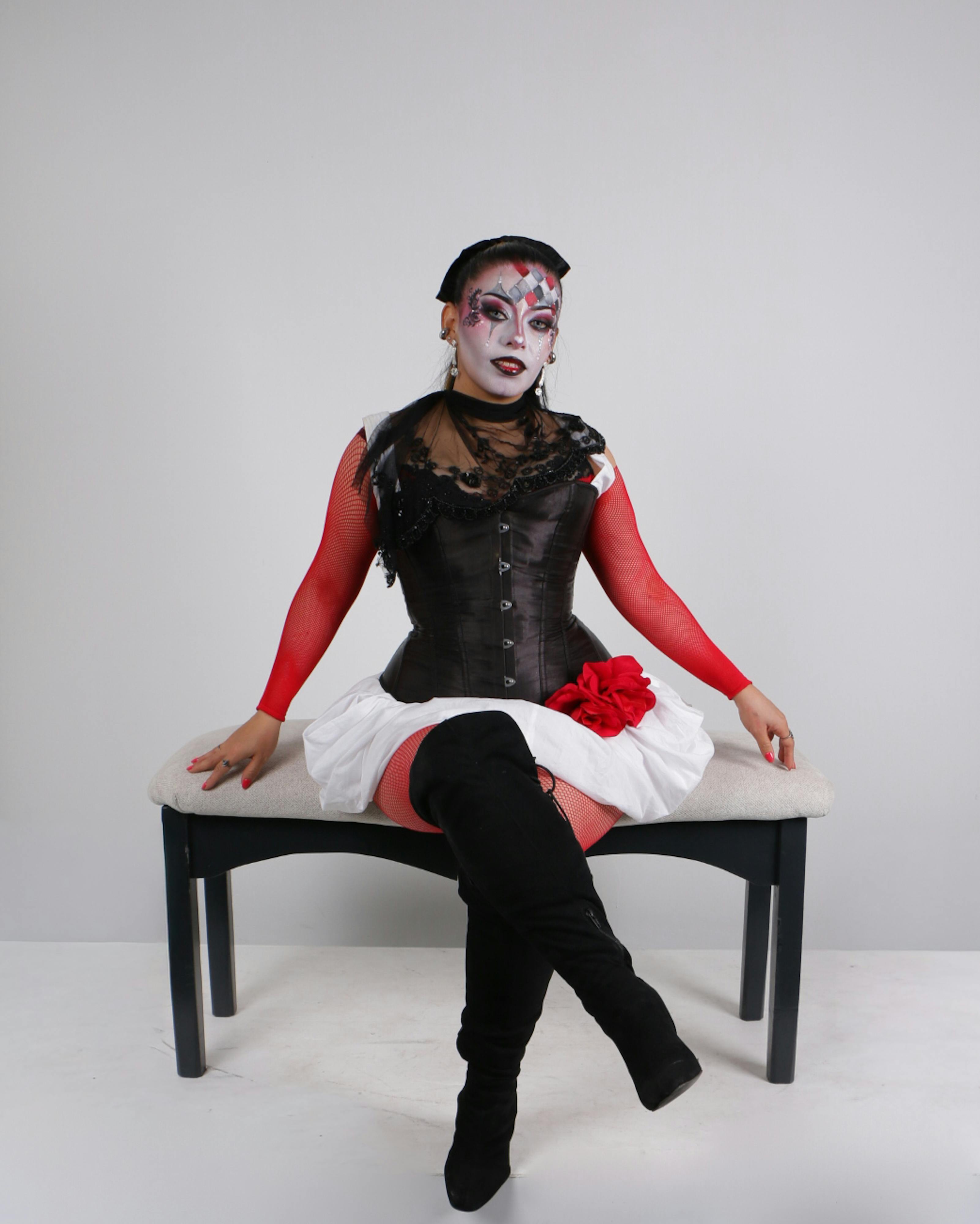 Ücretsiz Eşsiz bir kostüm ve cesur bir makyajla bir bankta oturan bir kadının büyüleyici portresi. Stok Fotoğraflar